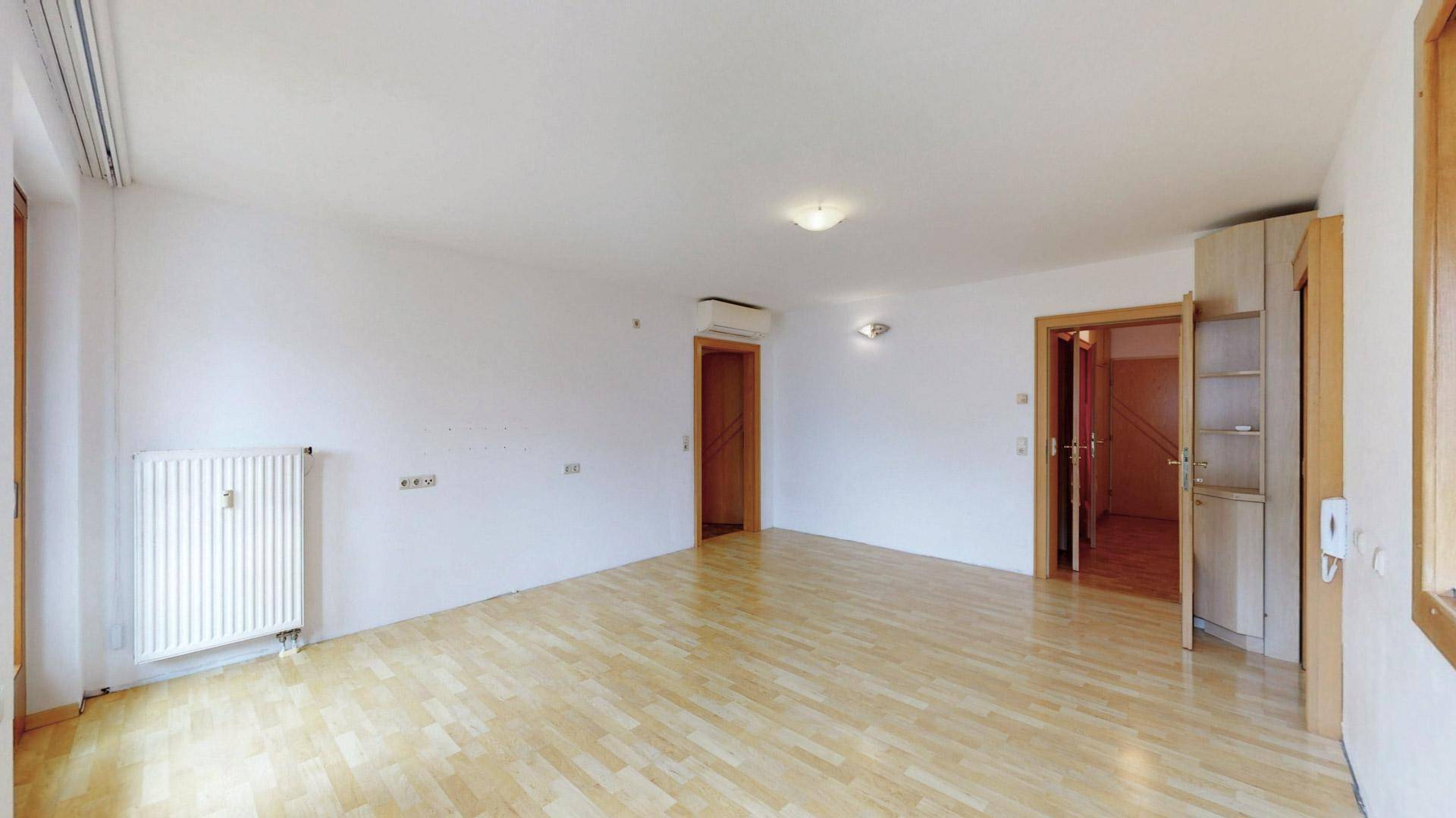 Heller Wohnbereich mit Holzboden, weißen Wänden und einem praktischen Einbauschrank.