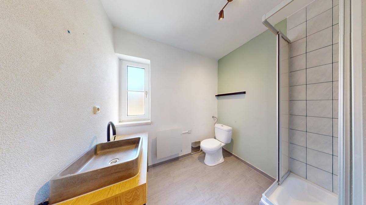 Modernes Badezimmer mit begehbarer Dusche, Fenster und einem stilvollen Waschbecken auf Holzunterschrank.