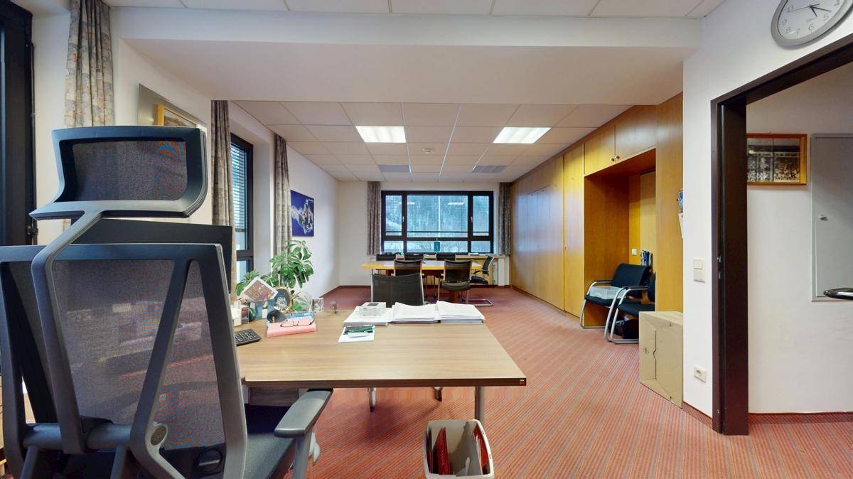 Büro mit Teppichboden, Schreibtisch und Stühlen, das eine professionelle Arbeitsumgebung bietet.