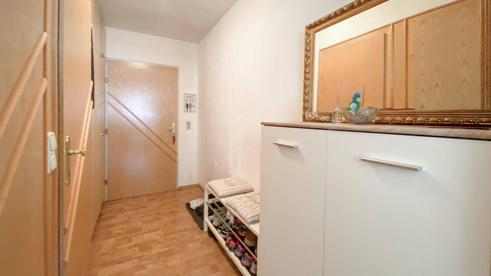 Heller Flur mit Schuhschrank, Spiegel und Holzboden.