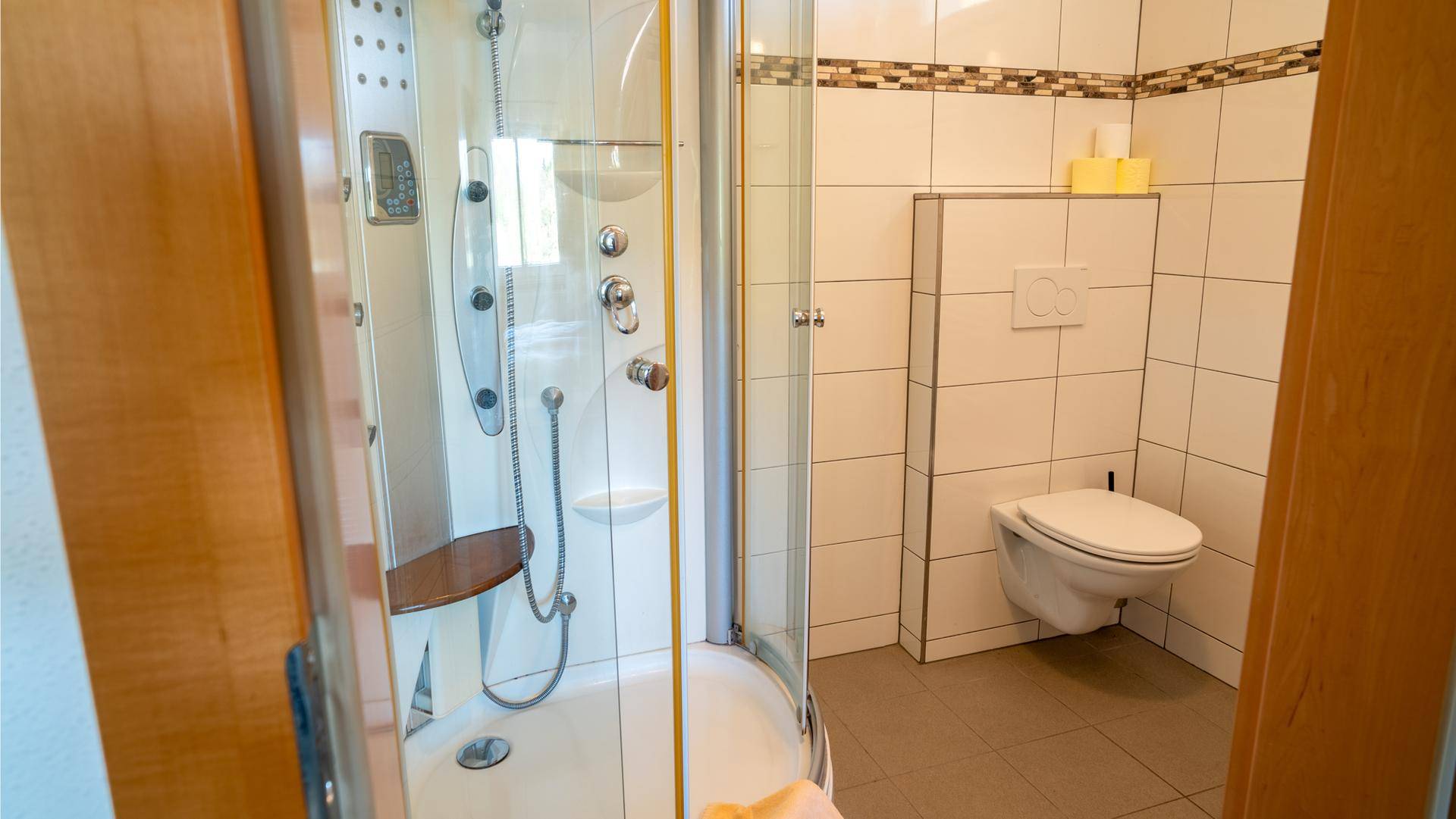 Modernes Badezimmer mit Duschkabine, wandhängendem WC und Fliesen.