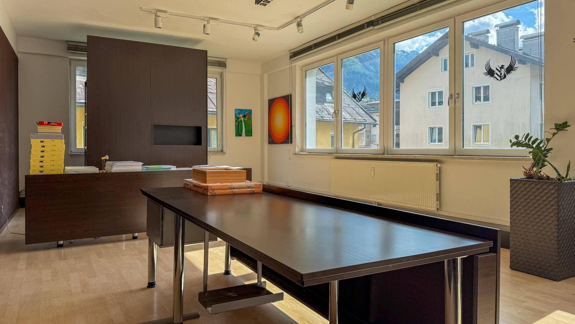 Heller Büroraum mit großen Fenstern, die einen Blick auf die Berge und umliegende Gebäude bieten.