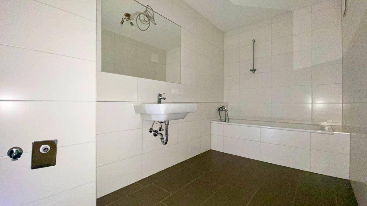 Modernes Badezimmer mit Badewanne, Waschbecken und großen Fliesen.