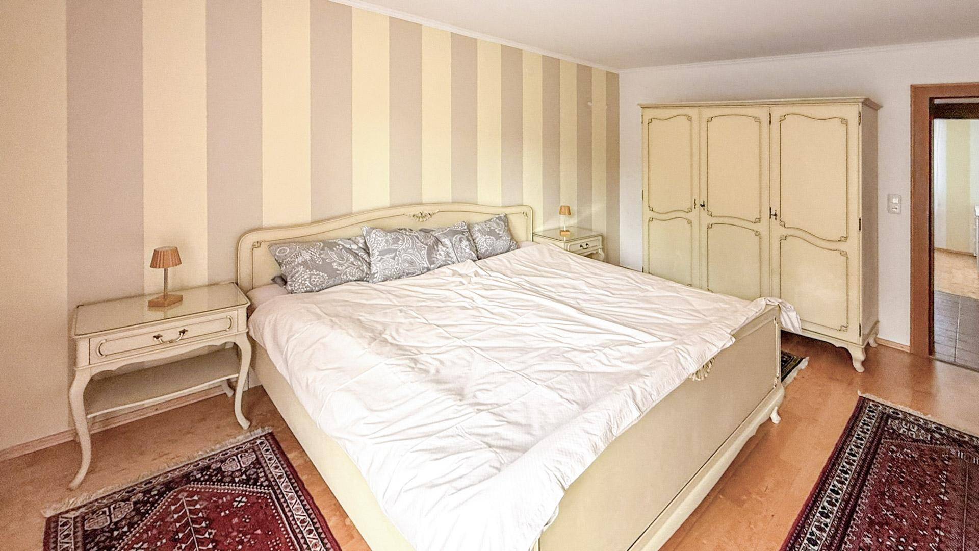 Gemütliches Schlafzimmer mit Doppelbett, Nachttischen und einem großen Kleiderschrank.