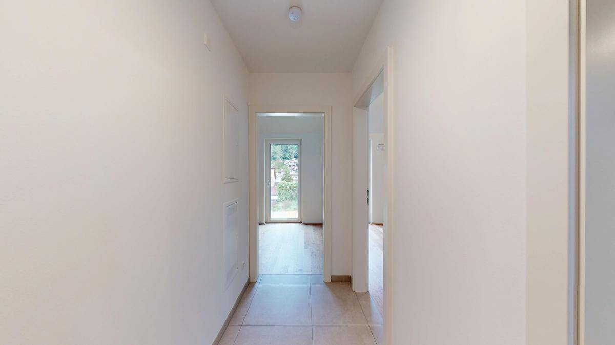Heller Flur mit Fliesenboden, der zu verschiedenen Räumen der Wohnung führt.