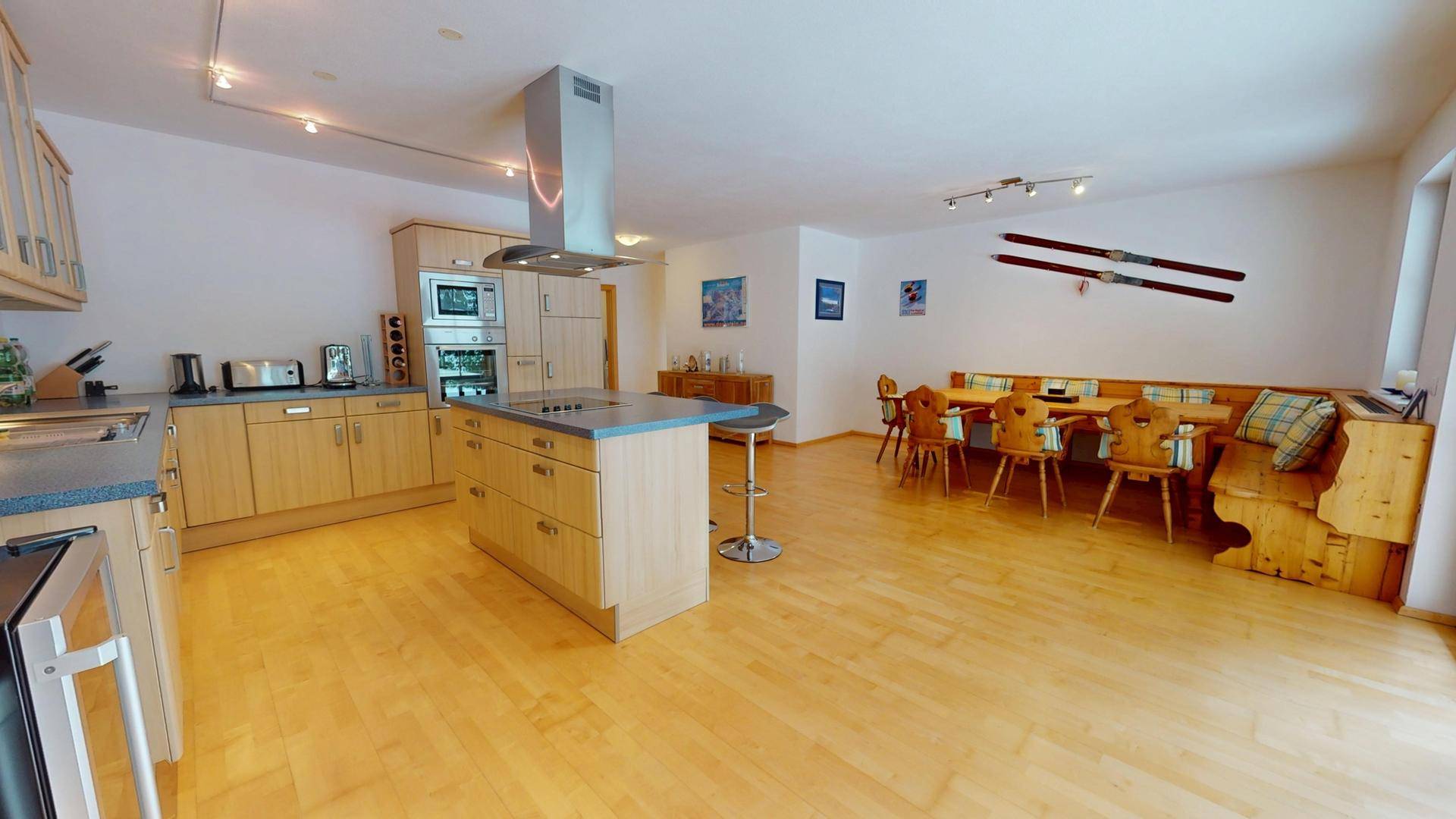 Moderne Holzküche mit Kücheninsel, integrierten Geräten und gemütlichem Essbereich.