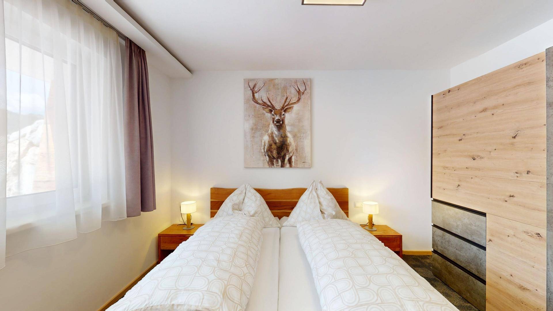 Gemütliches Schlafzimmer mit Doppelbett, Hirschmotiv und Holzschrank.