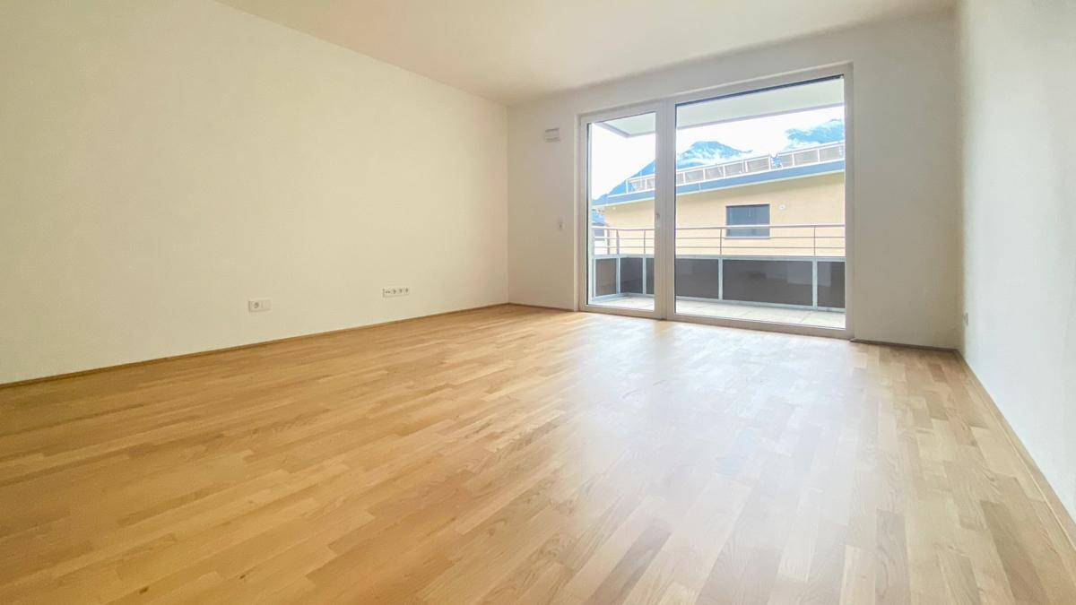 Geräumiger, heller Raum mit Parkettboden und Zugang zu einem Balkon mit Bergblick.