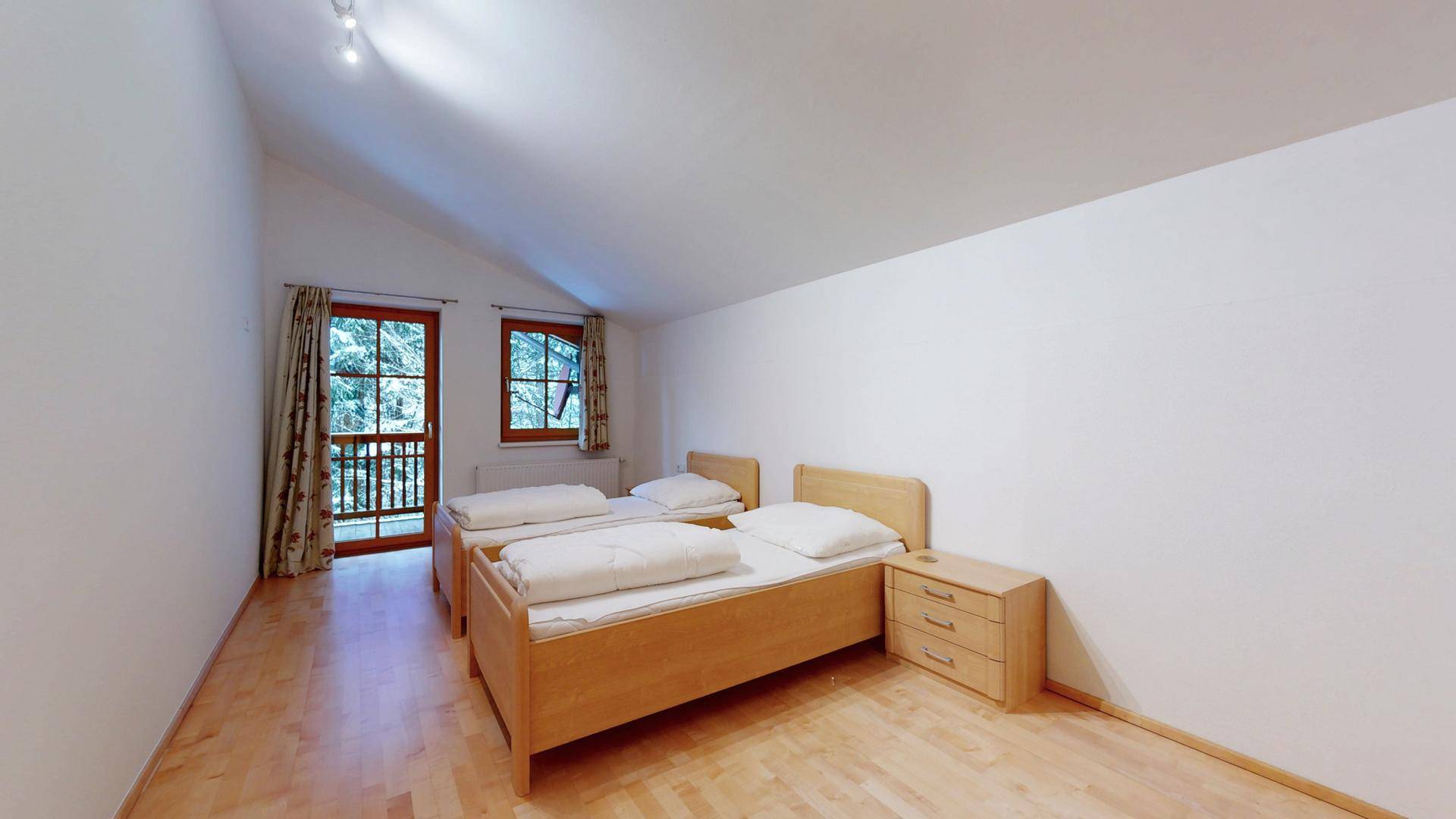 Helles Schlafzimmer mit zwei Einzelbetten und Zugang zu einem kleinen Balkon.