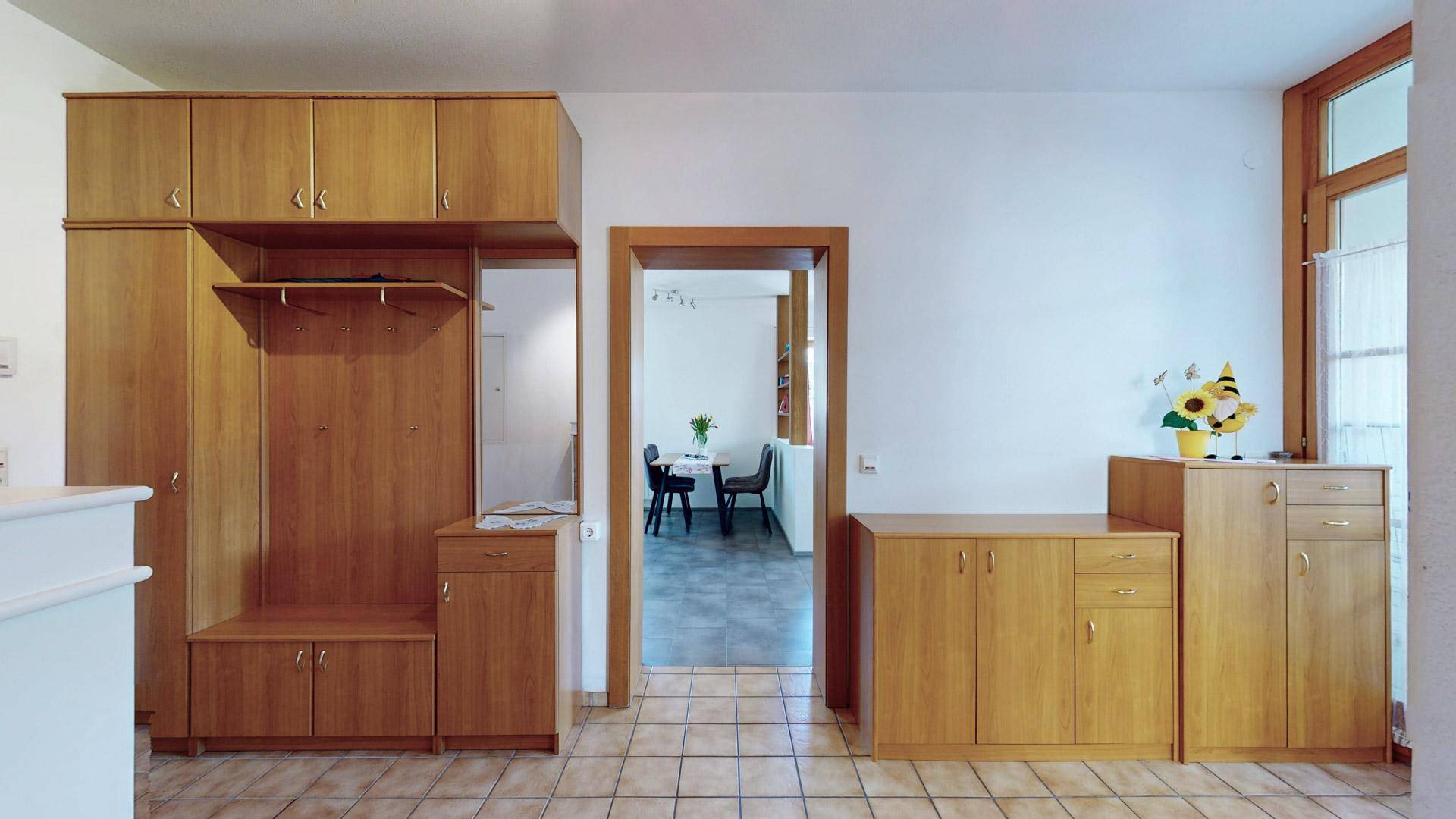 Eingangsbereich mit praktischen Holzschränken und Garderobe, ideal für Stauraum.