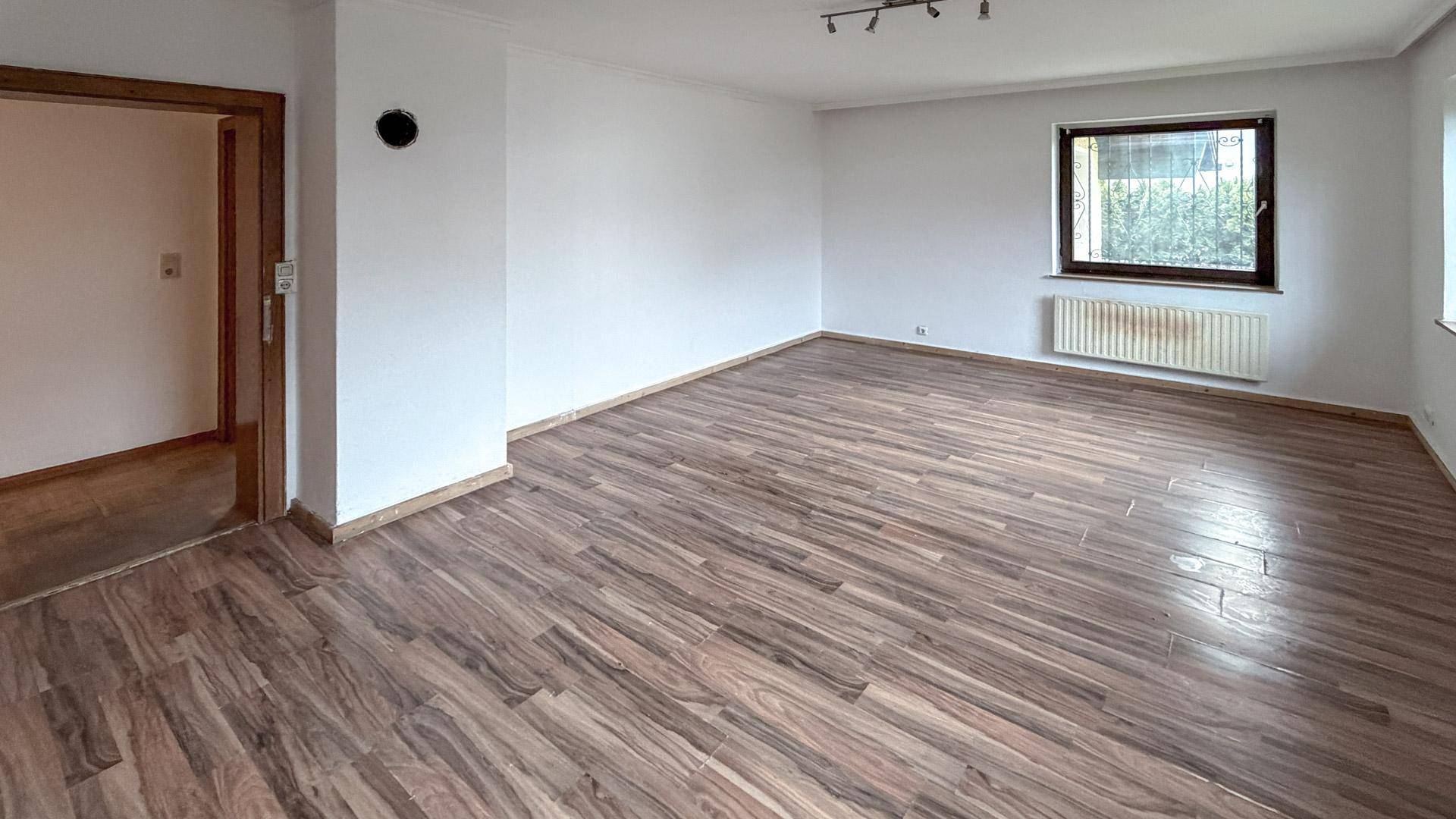 Geräumiges Zimmer mit Laminatboden und Fenster, ideal als Wohn- oder Schlafzimmer.