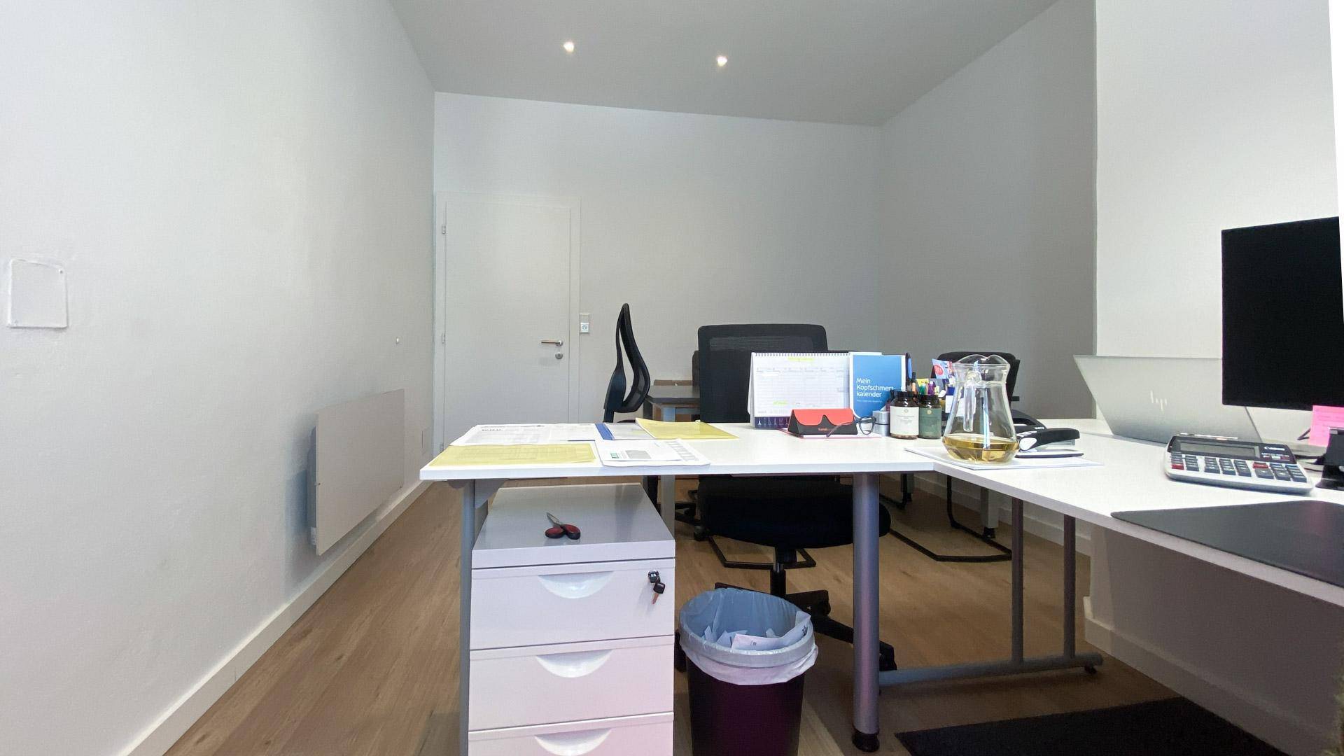 Moderner Arbeitsplatz in einem hellen Büro mit Schreibtisch, Computer und Rollcontainer.