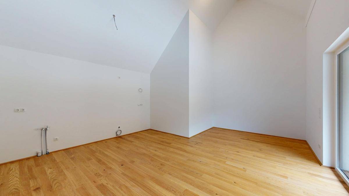 Geräumiger Wohnbereich mit Holzboden und hohen Decken, bereit für die individuelle Gestaltung.