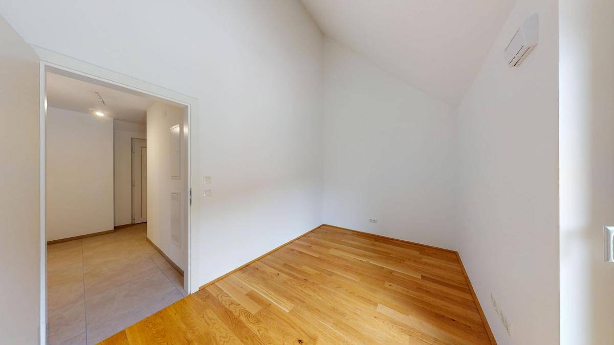 Gemütliches Zimmer mit Holzboden und Zugang zu einem weiteren Bereich der Wohnung.