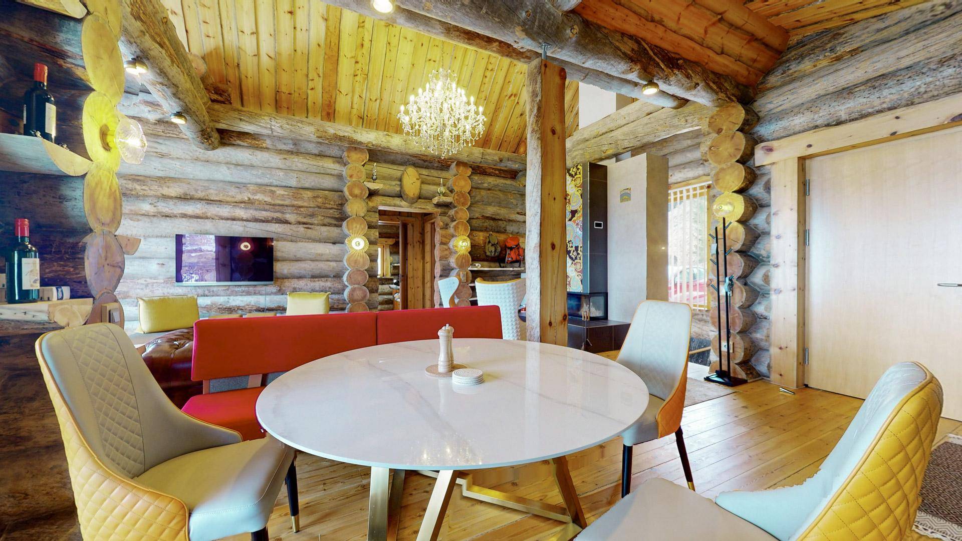 Gemütlicher Essbereich mit rundem Tisch, gepolsterten Stühlen und Holzwänden im Chalet-Stil.