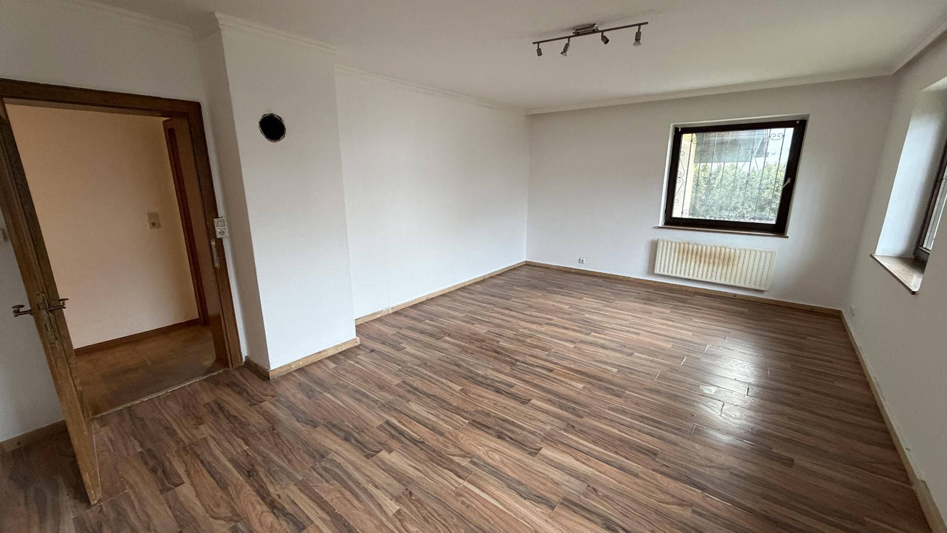Helles Zimmer mit modernem Laminatboden und zwei Fenstern für viel Tageslicht.