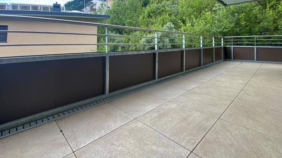 Großer Balkon mit moderner Brüstung und freiem Blick auf die bewaldeten Hügel.