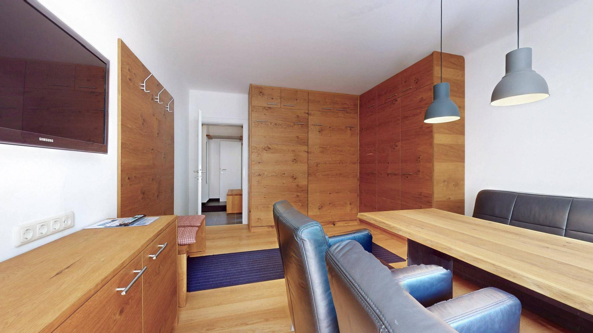 Gemütlicher Wohn- und Essbereich mit Holzelementen, Esstisch und Fernseher an der Wand.