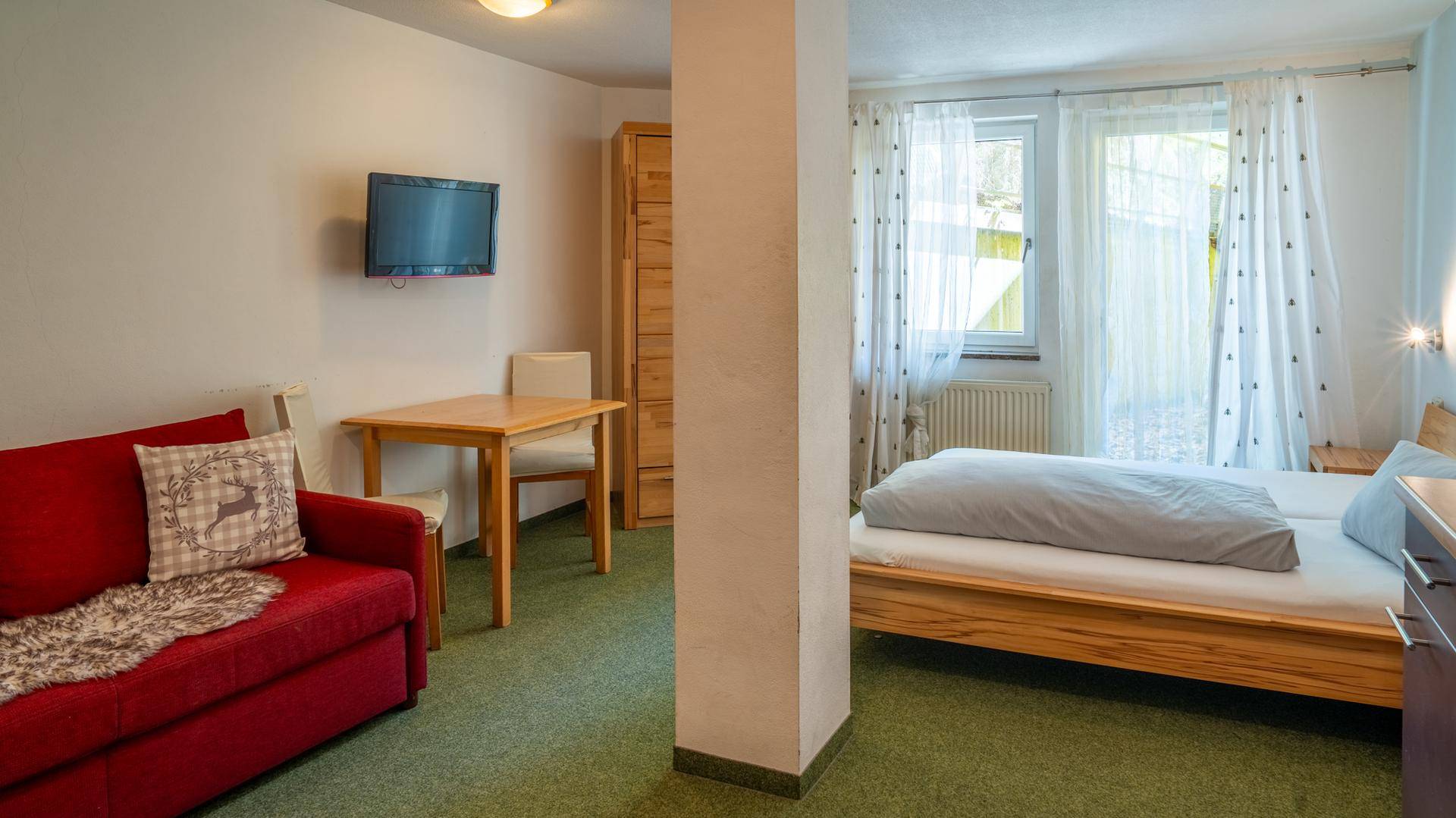 Geräumiges Schlafzimmer mit Doppelbett, Sofa und Esstisch, hell und funktional eingerichtet.