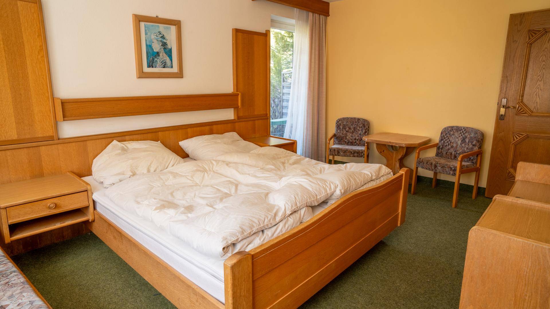 Traditionelles Schlafzimmer mit Holzmöbeln, Teppichboden und gelben Wänden.