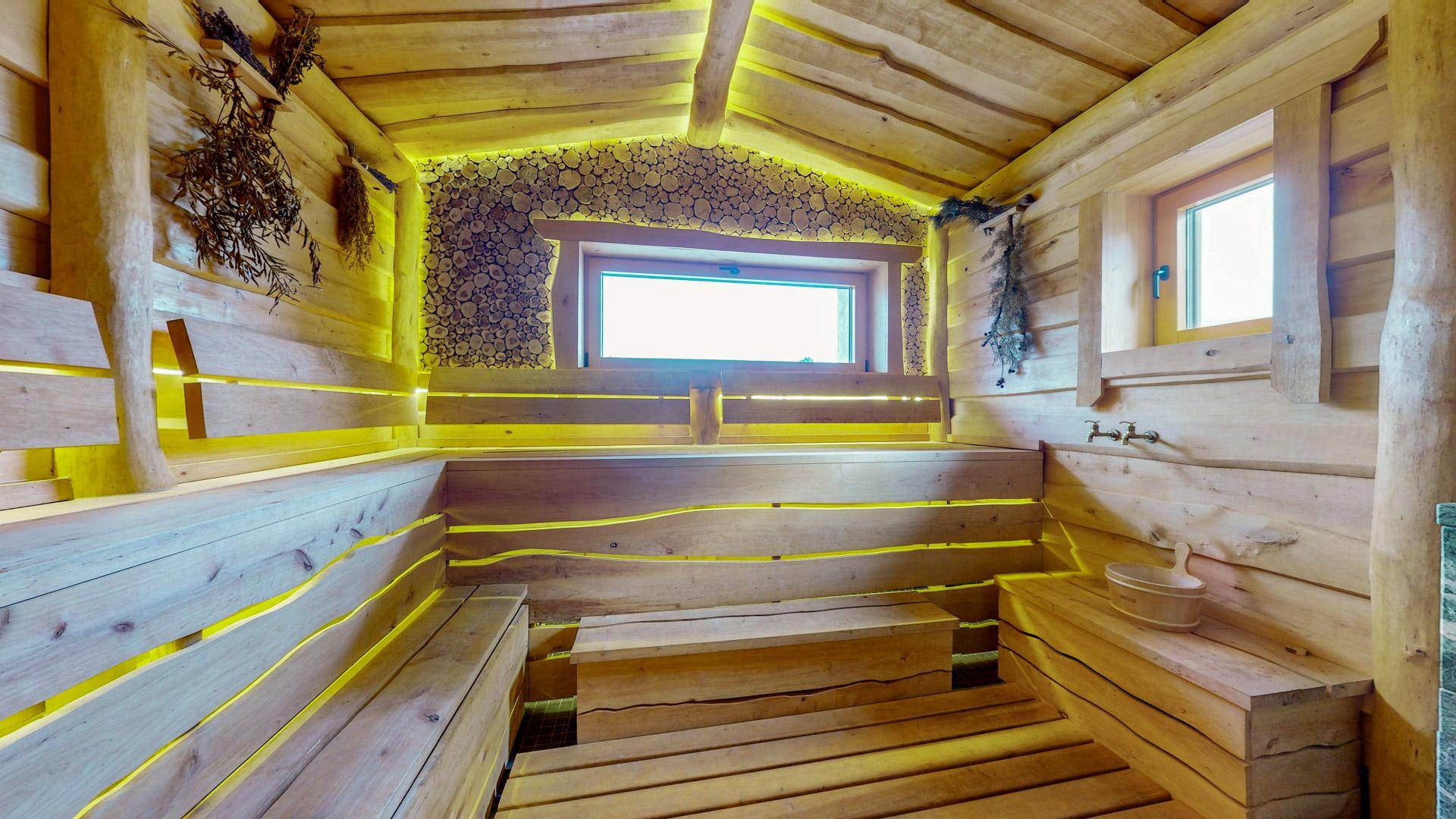 Rustikale Holzsauna mit indirekter Beleuchtung und Sitzbänken, die eine entspannende Atmosphäre schaffen.
