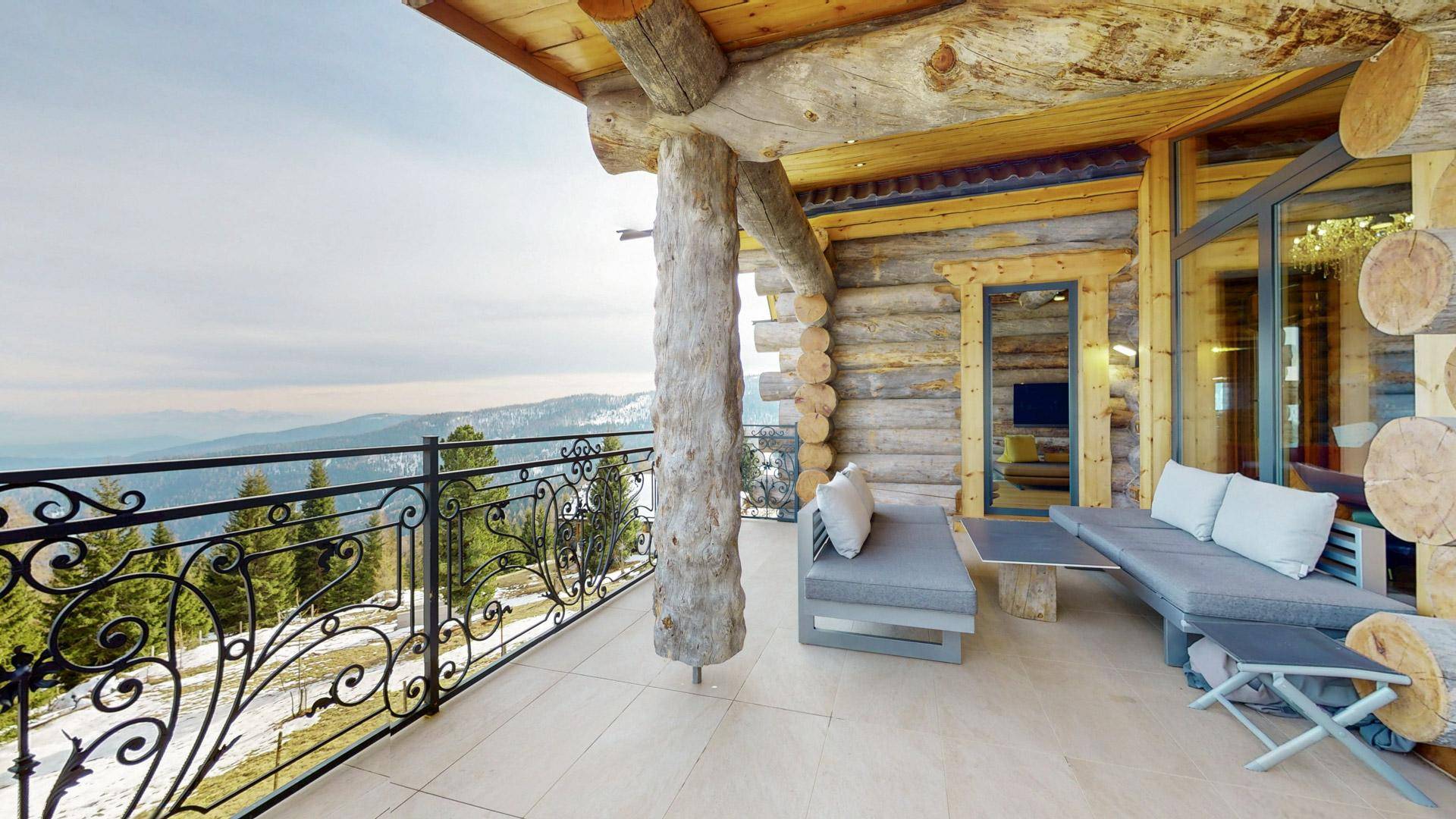 Geräumiger Balkon mit bequemen Loungemöbeln und einem atemberaubenden Blick auf die verschneiten Berge.