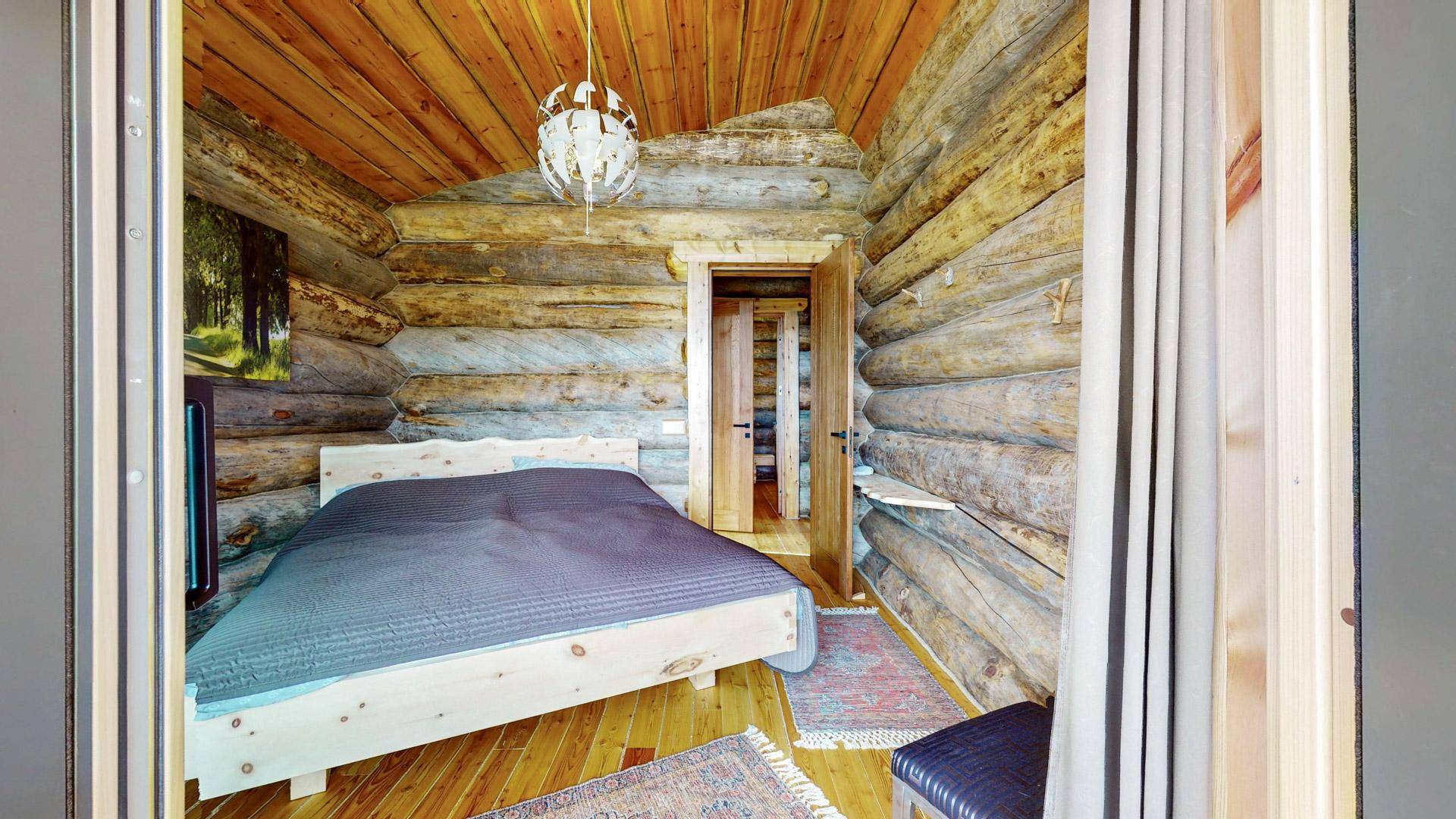 Schlafzimmer im rustikalen Stil mit Holzwänden, Holzboden und einem gemütlichen Doppelbett.