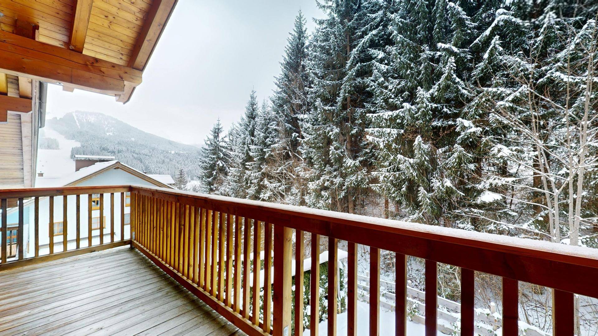 Großer Holzbalkon mit Geländer und weitem Blick auf die verschneite Berglandschaft.