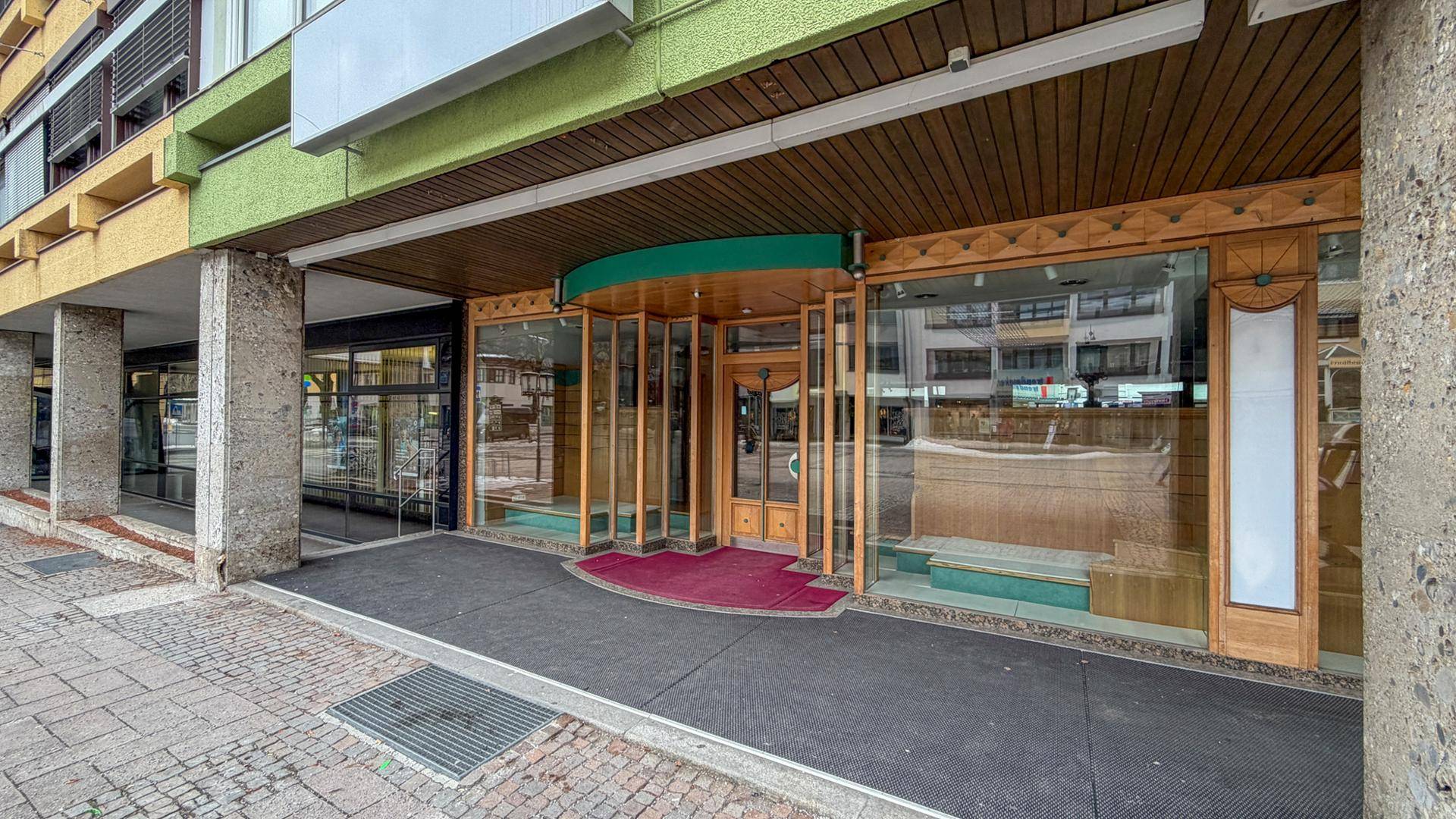 Fassade eines Geschäftsgebäudes mit großen Glasfronten und einem überdachten Eingangsbereich.