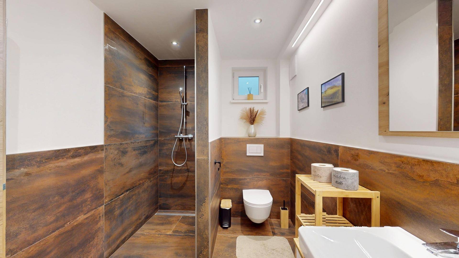Modernes Badezimmer mit ebenerdiger Dusche, WC und rustikalen Fliesen.