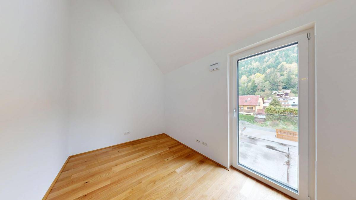 Helles Zimmer mit Holzboden und Zugang zu einem kleinen Balkon oder französischen Balkon.