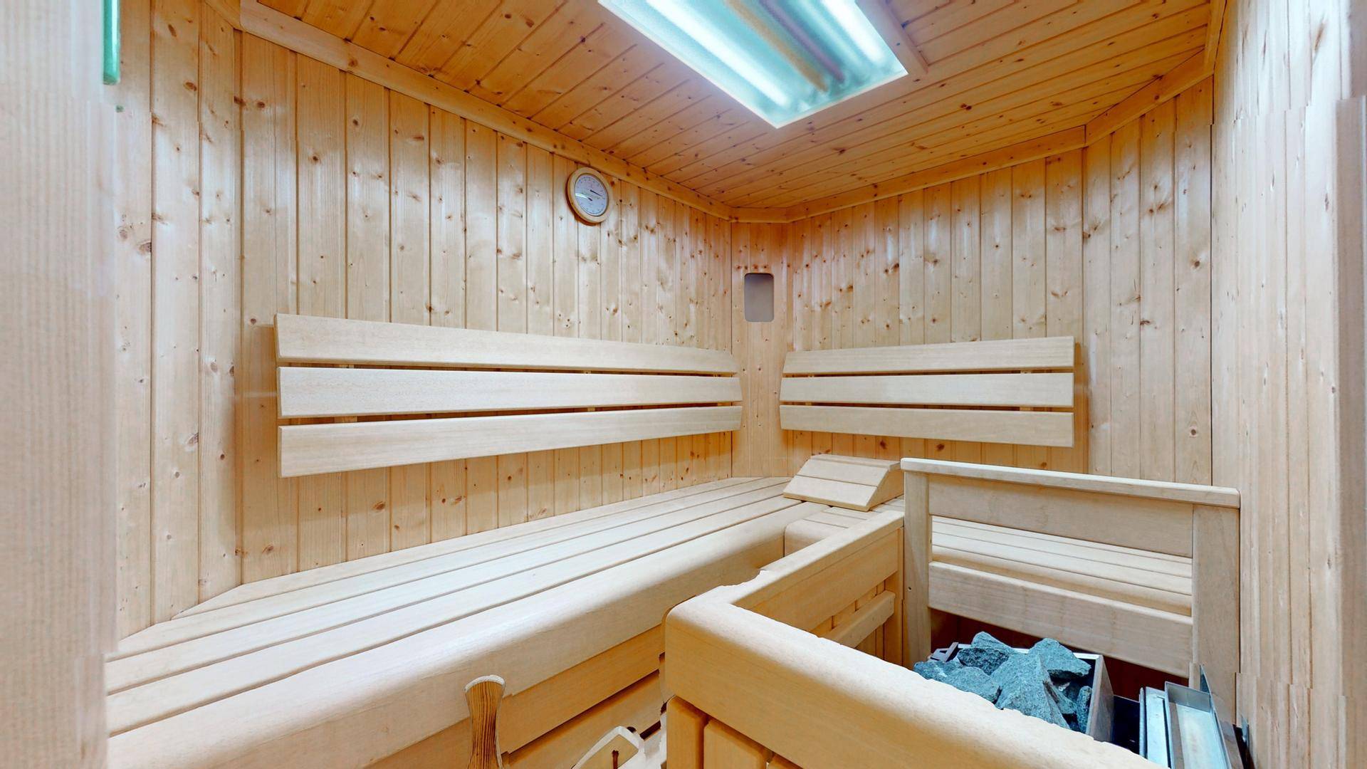 Innenansicht der Holzsauna mit Bänken und traditionellem Saunaofen.
