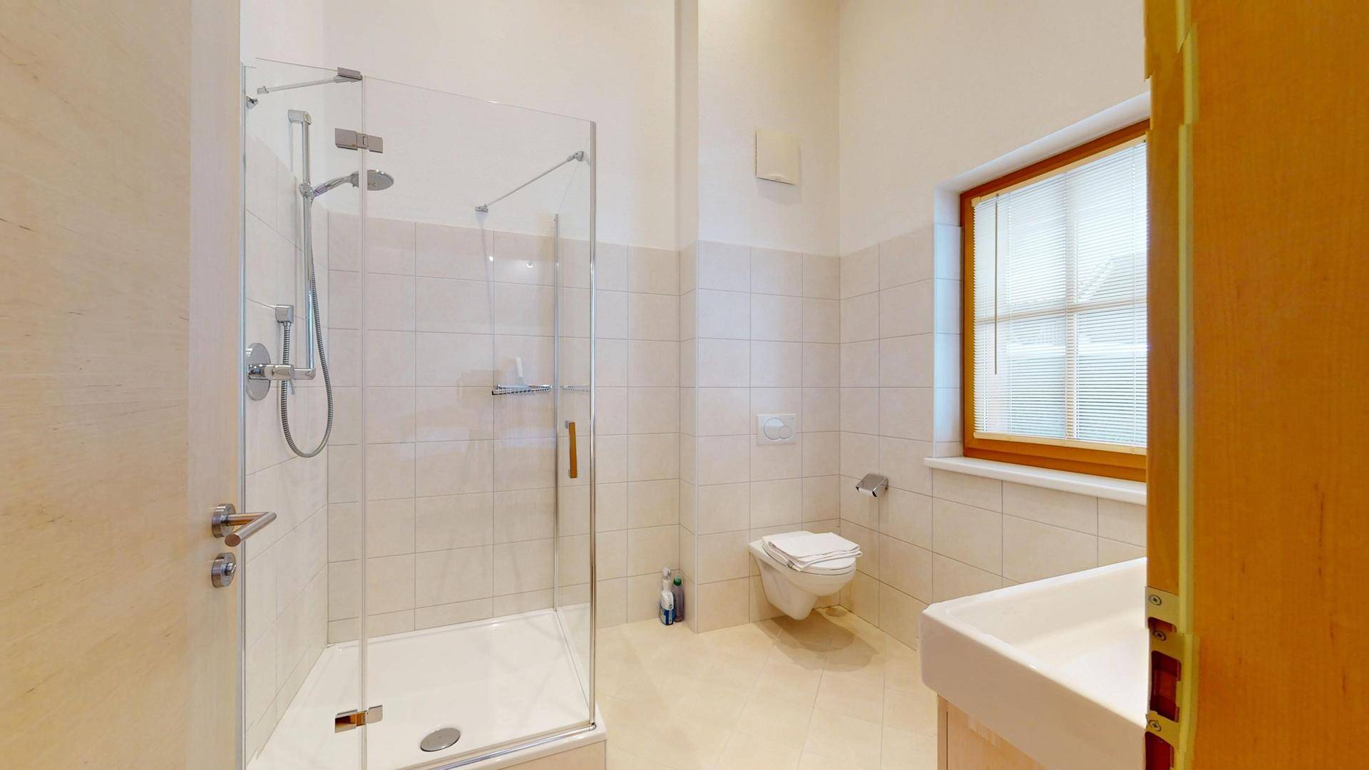 Modernes Badezimmer mit Duschkabine, Wand-WC und Fenster für Tageslicht.