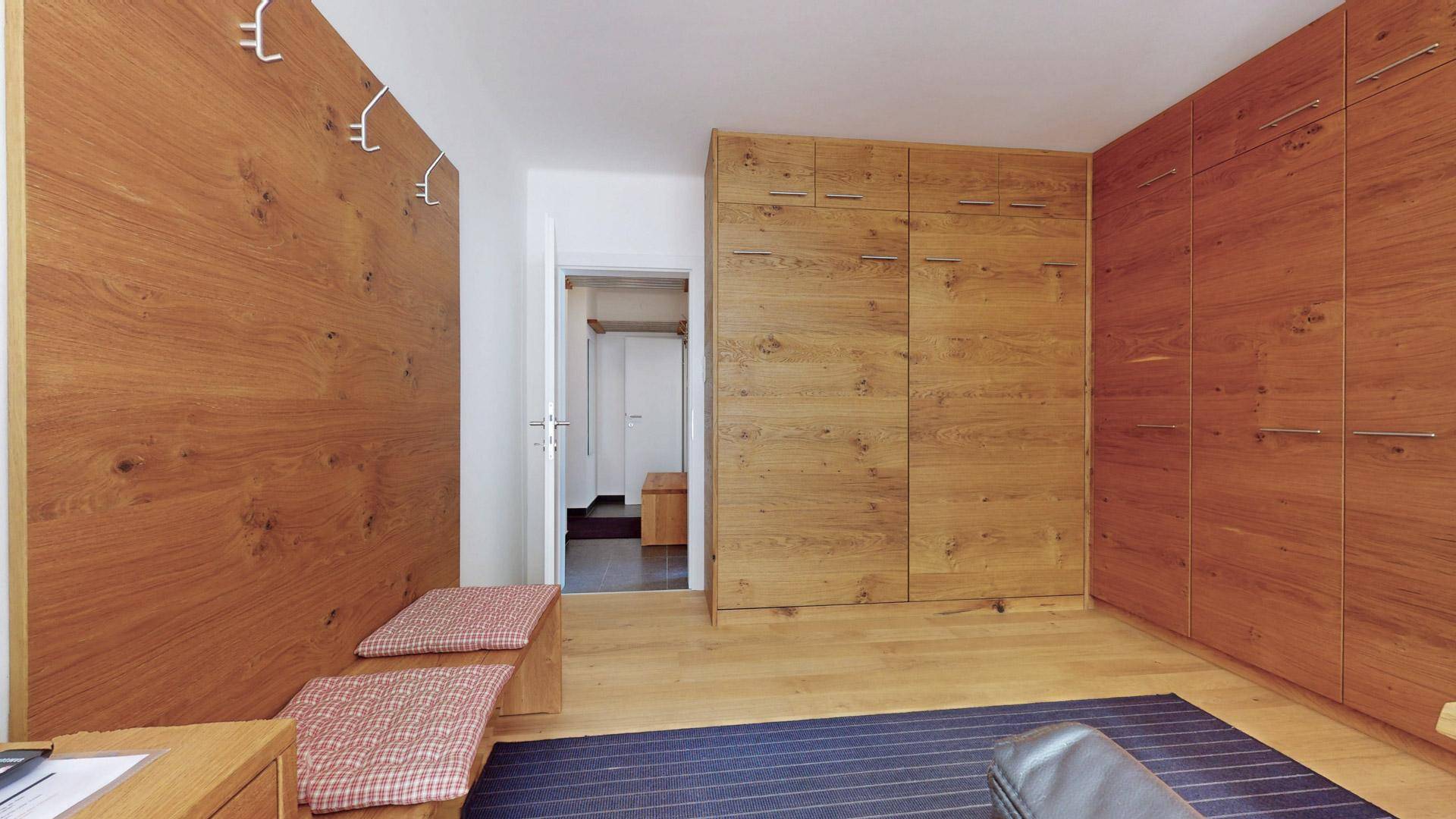 Eingangsbereich mit integrierten Holzschränken, Sitzbank und Garderobe für praktischen Stauraum.