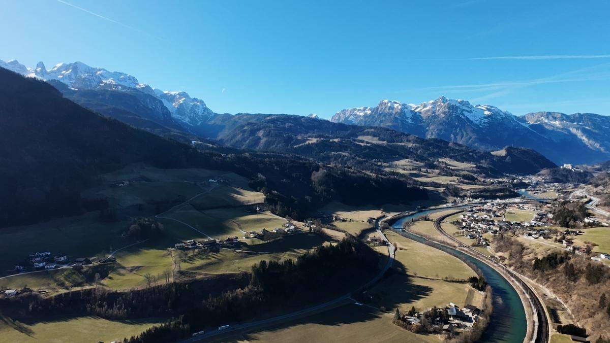 Weitläufige Luftaufnahme eines Tals mit Bergen, einem Fluss und einer kleinen Stadt in der Ferne.