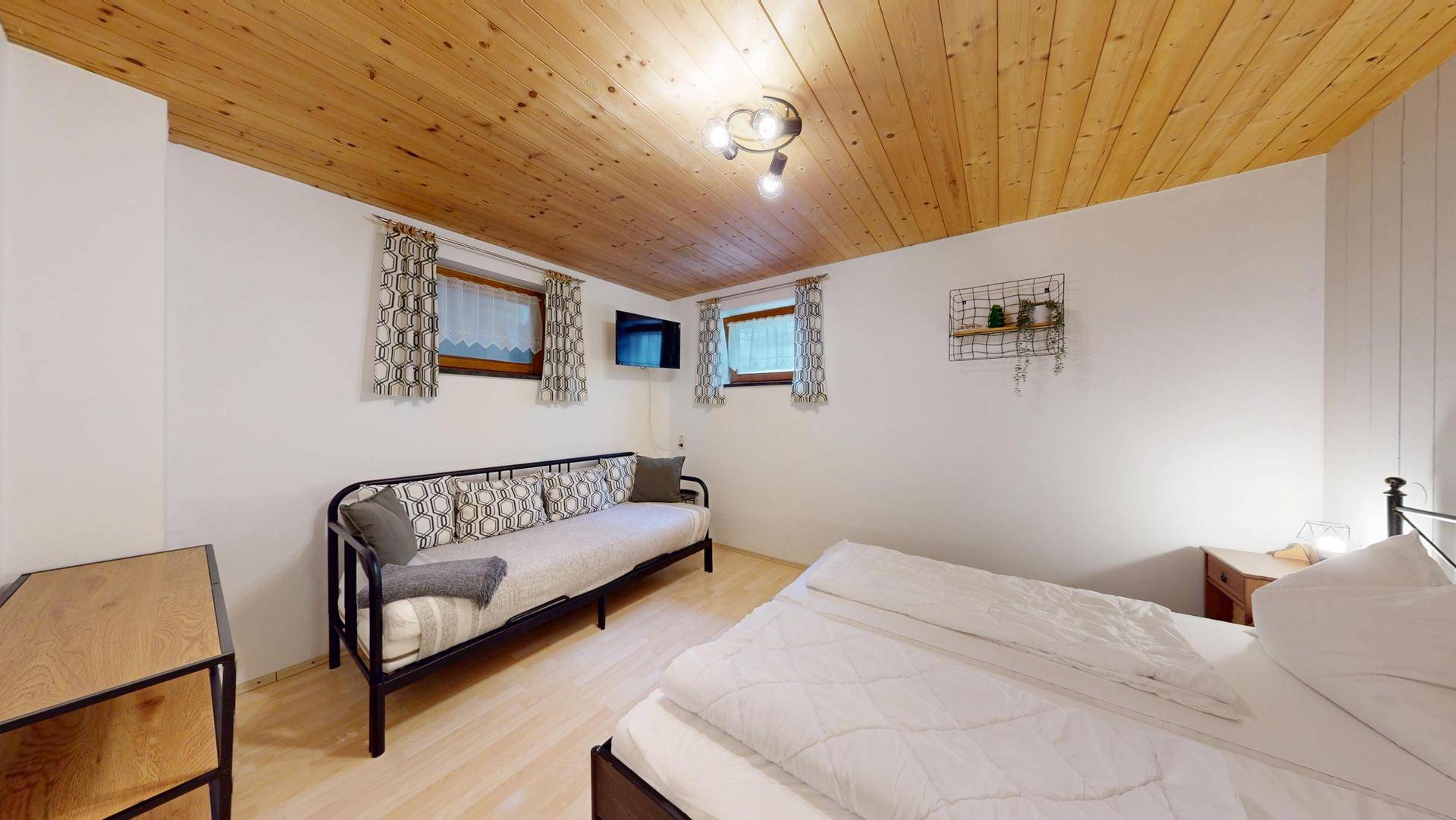 Geräumiges Schlafzimmer mit Doppelbett und zusätzlichem Tagesbett, ideal für Gäste.