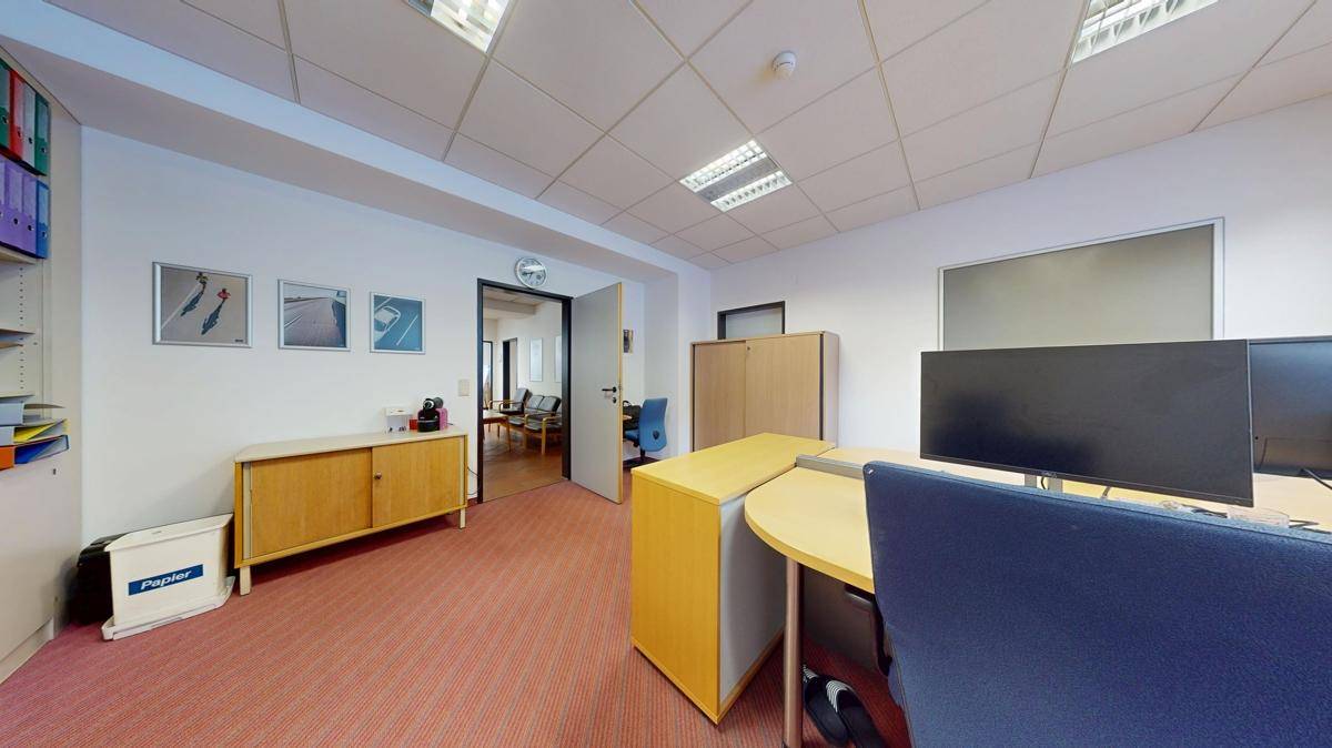 Büro mit Teppichboden, Schreibtisch und Holzschränken, die eine funktionale Arbeitsumgebung bieten.