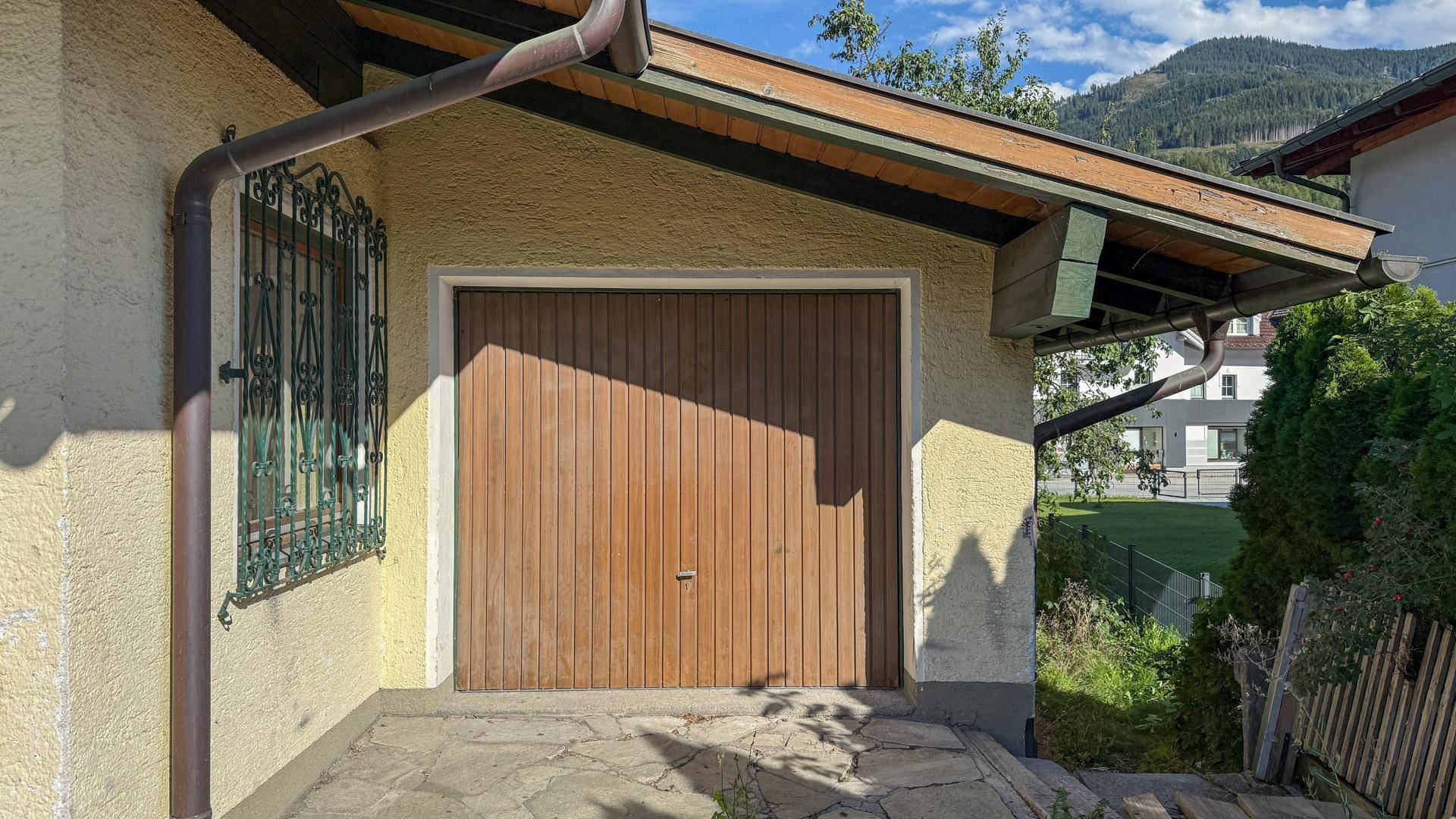 Holzgaragentor des Hauses mit traditionellen Fenstergittern und schützendem Dachüberstand.