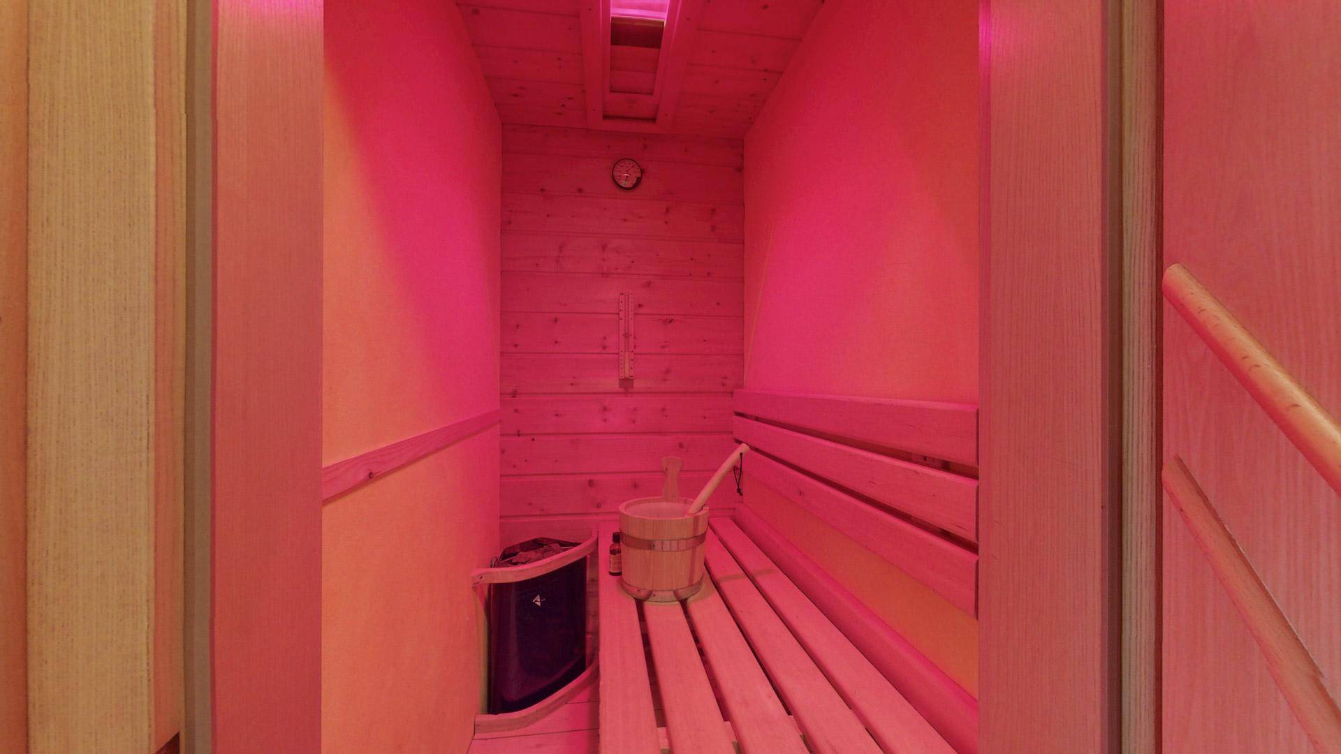 Gemütliche Sauna mit Holzverkleidung, Bänken und stimmungsvoller Beleuchtung.