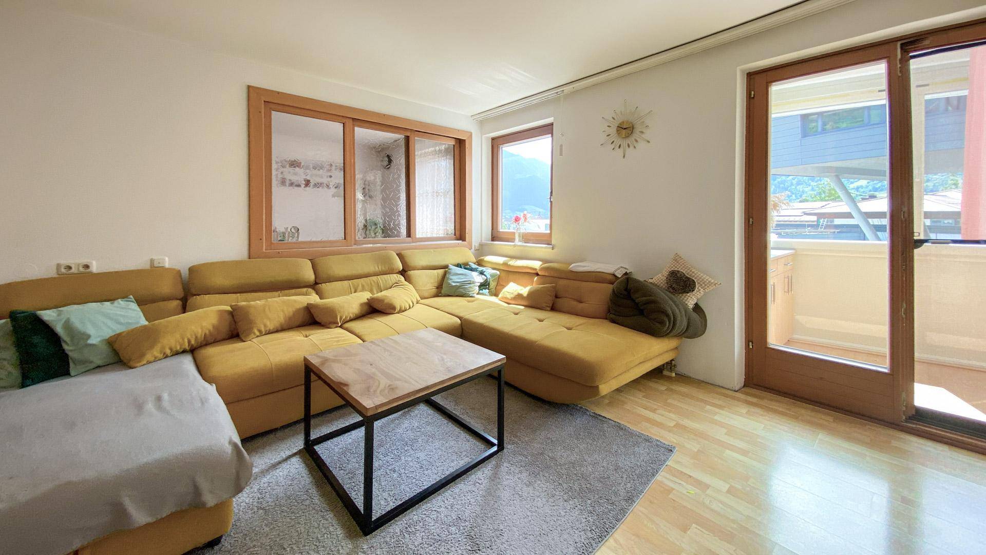 Wohnzimmer mit großem Ecksofa, Couchtisch und Zugang zum Balkon.