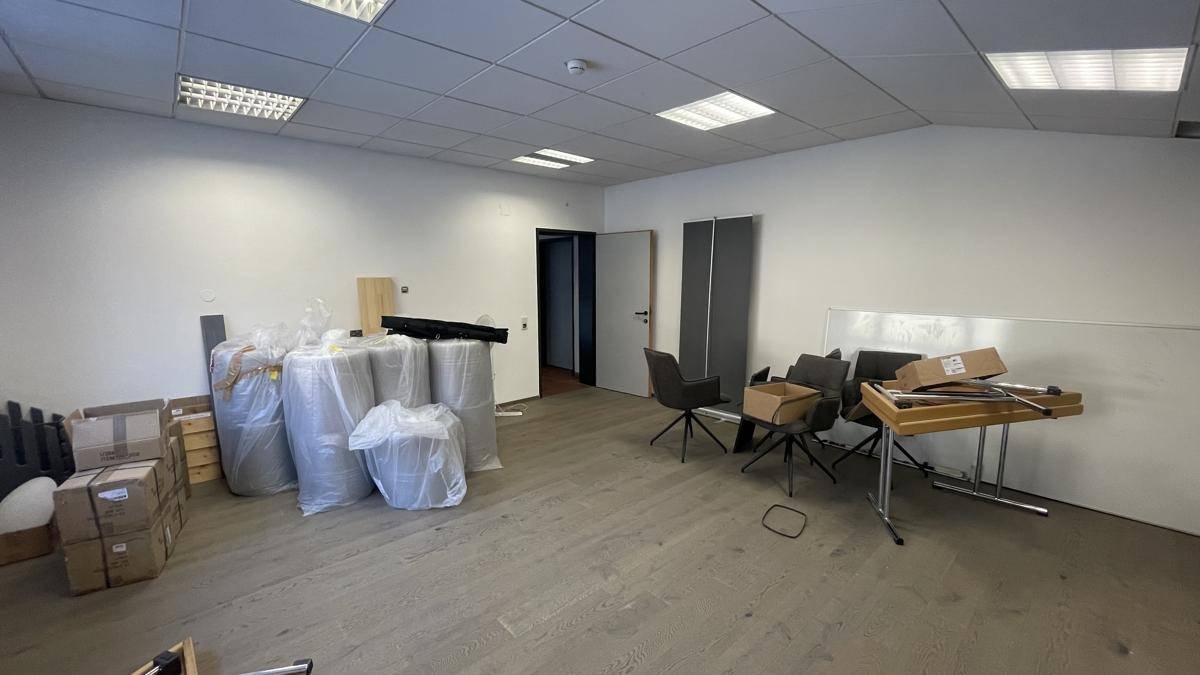 Unmöblierter Raum mit hellem Boden und gestapelten Materialien, bereit für die Einrichtung oder Lagerung.