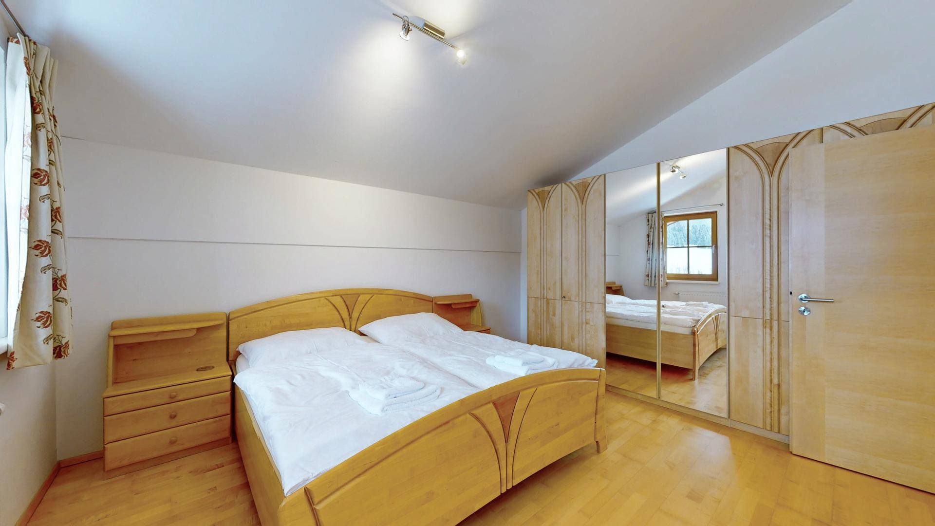 Schlafzimmer mit Doppelbett und geräumigen Einbauschränken mit Spiegeltüren.