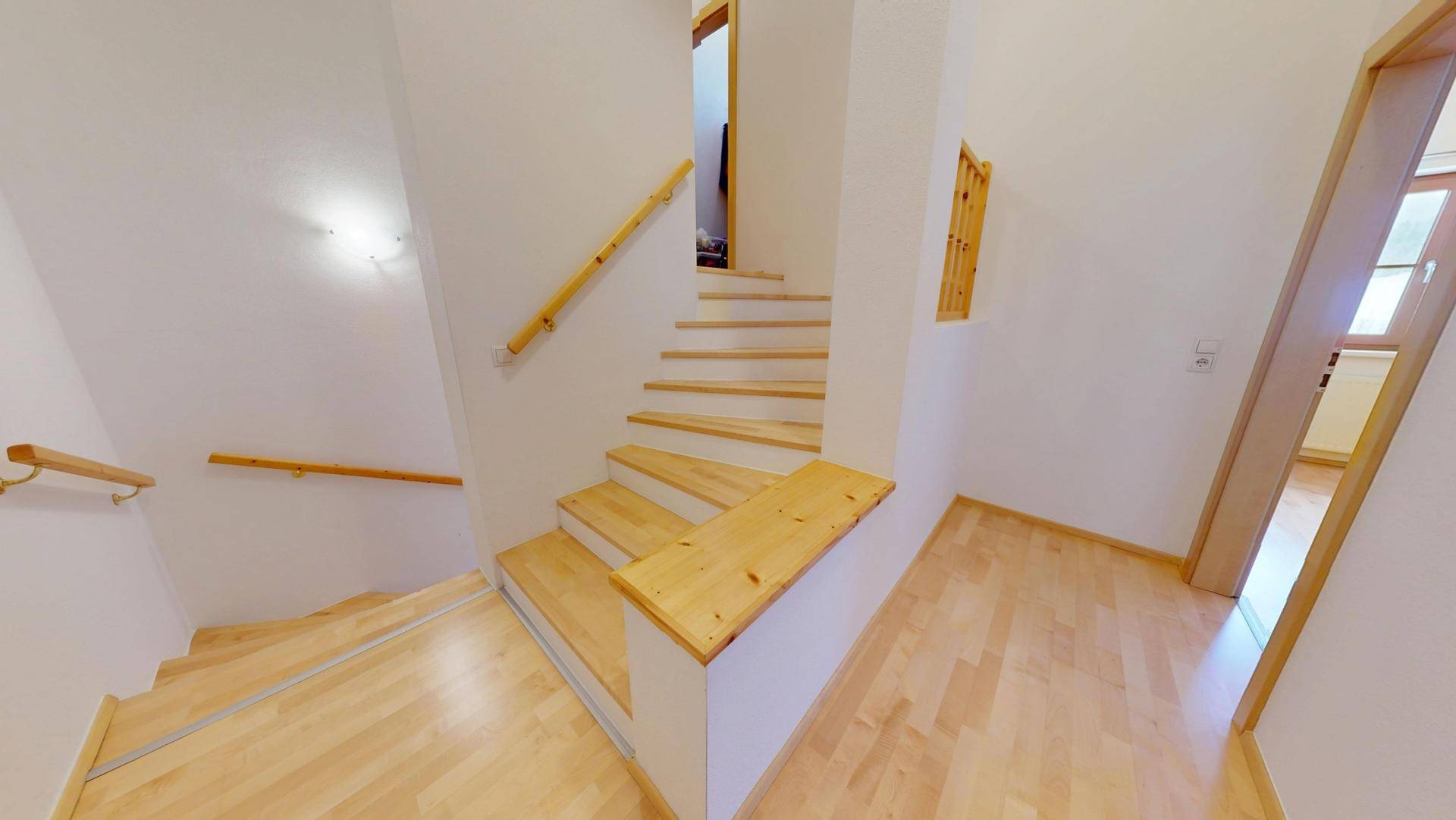 Helle Holztreppe mit Geländer, die die verschiedenen Ebenen des Hauses verbindet.