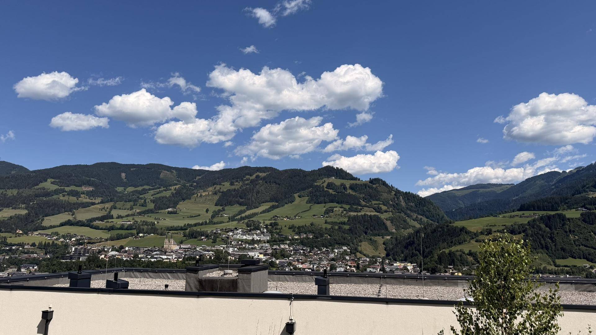 Atemberaubender Ausblick auf eine malerische Stadt im Tal, umgeben von sanften grünen Hügeln.
