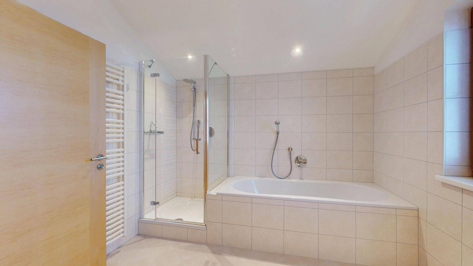 Geräumiges Badezimmer mit Badewanne, Duschkabine und beheiztem Handtuchhalter.