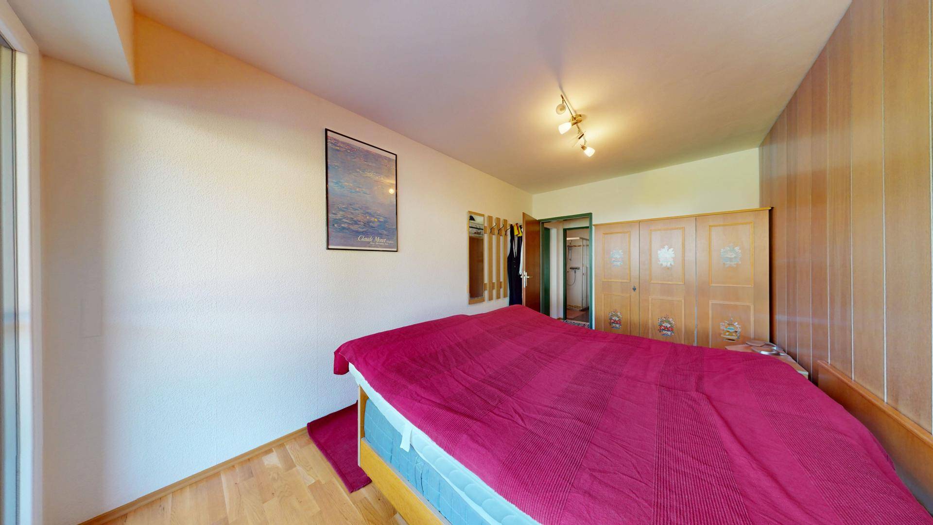Schlafzimmer mit Doppelbett, Holzboden und einem großen Kleiderschrank.