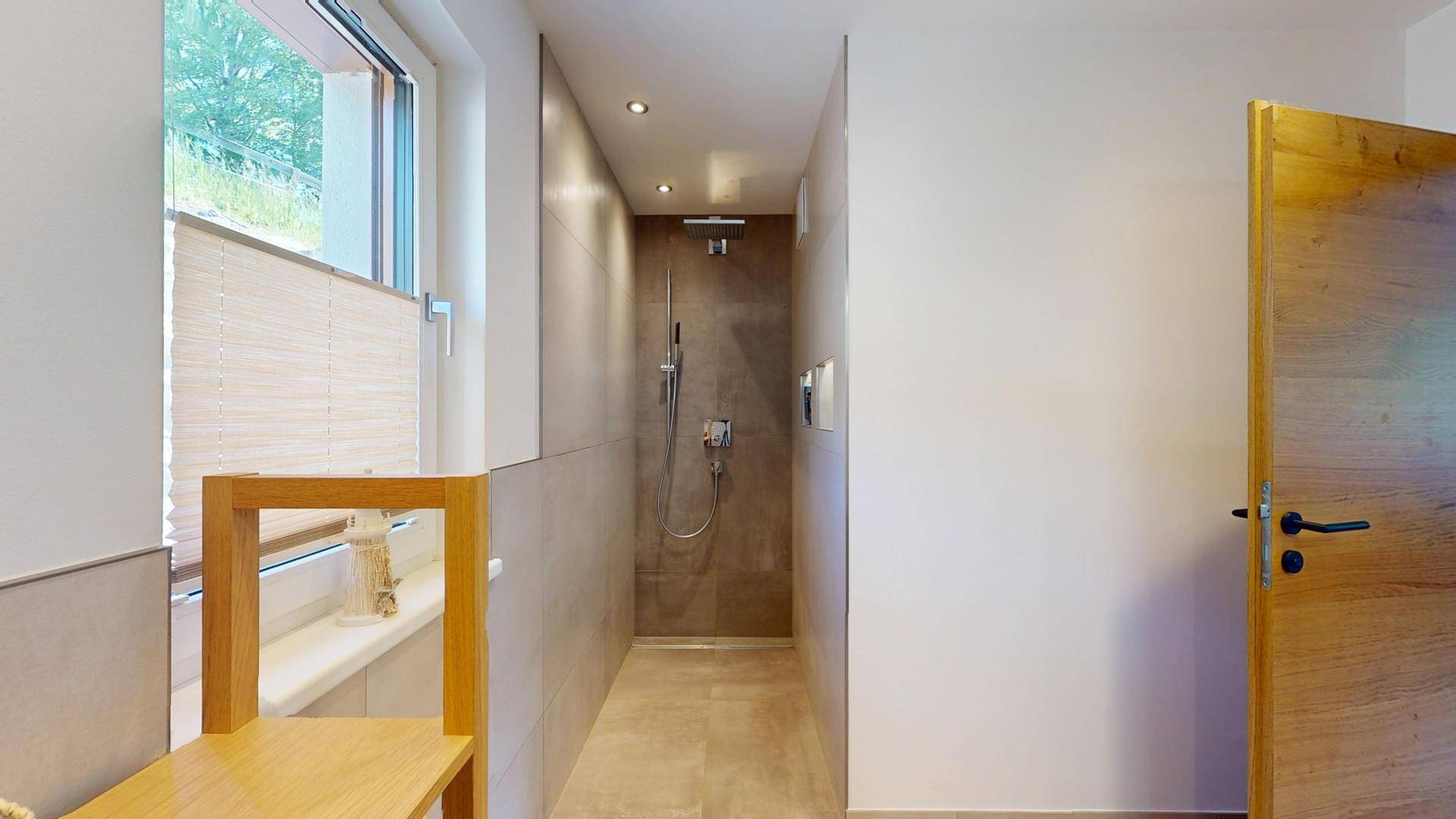 Modernes Badezimmer mit ebenerdiger Dusche, hellen Fliesen und Fenster.