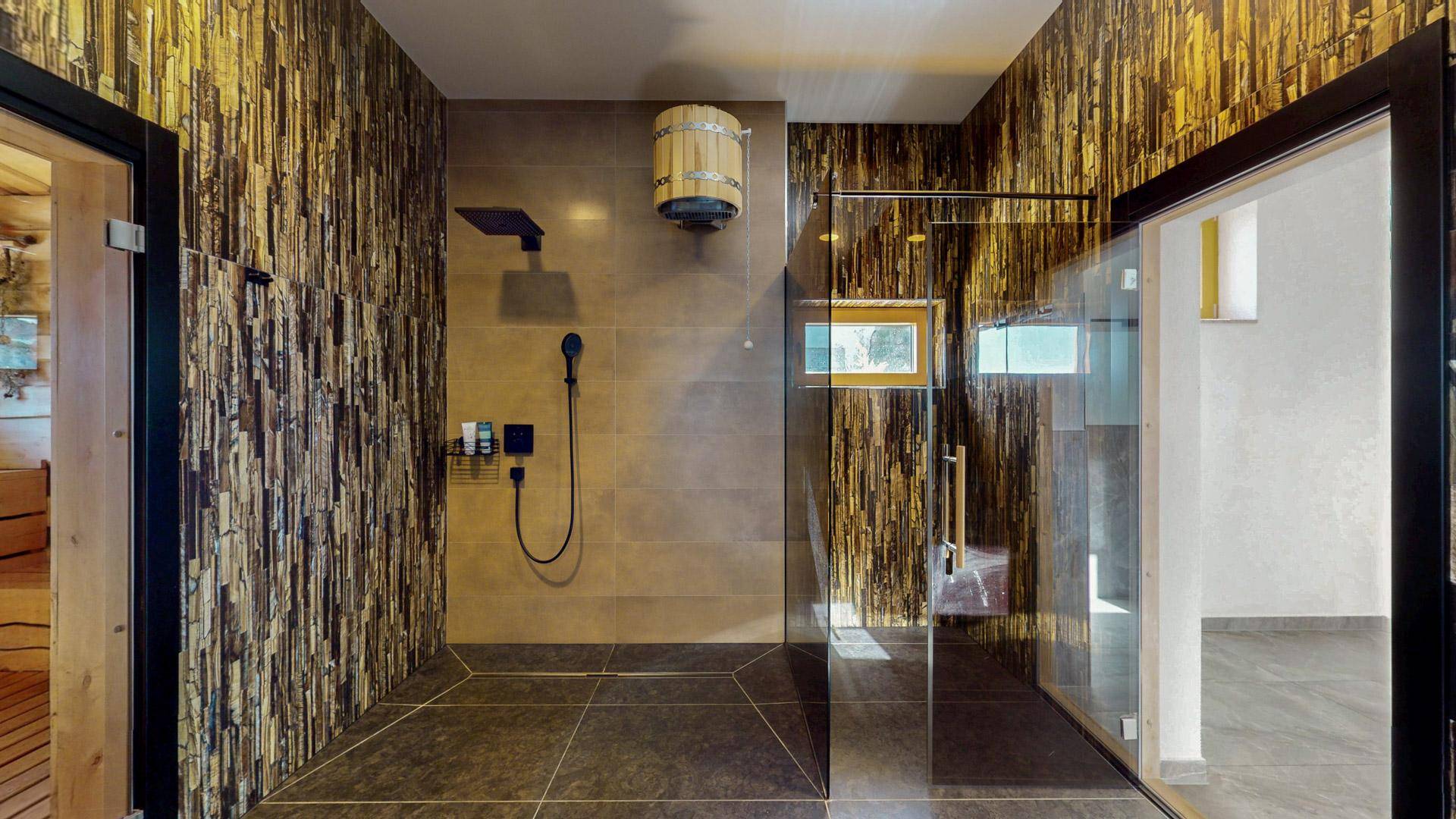 Modernes Badezimmer mit großer Duschkabine, stilvollen Fliesen und einem Holzeimer als Dekoration.