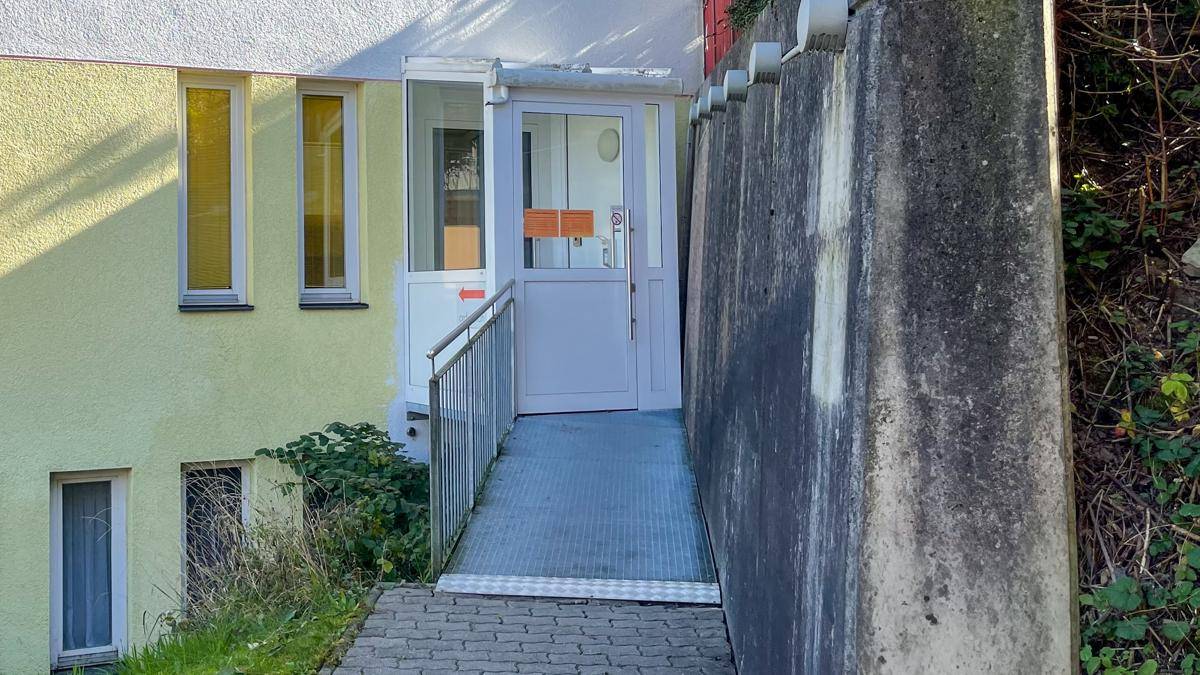 Barrierefreier Eingangsbereich mit Rampe und Geländer, der einen einfachen Zugang zum Gebäude ermöglicht.
