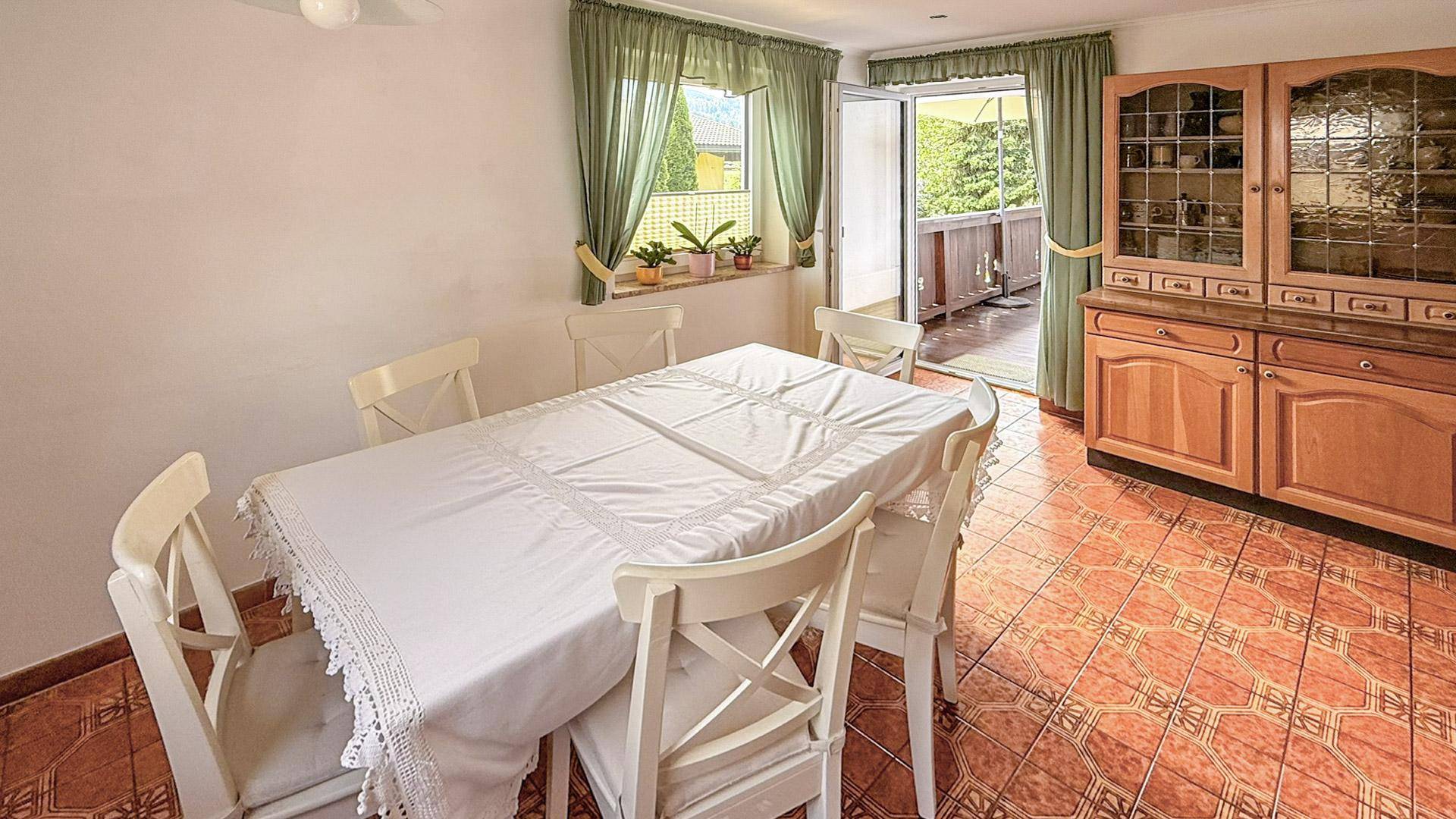 Essbereich mit Holztisch, Stühlen, traditionellem Schrank und direktem Zugang zum Balkon.